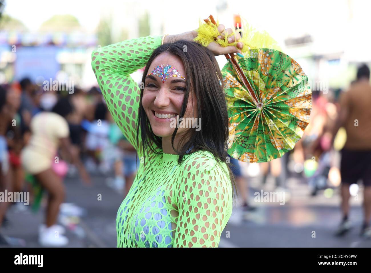 Das Mädchen in Grün stiehlt mit ihrer bunten Kleidung Aufmerksamkeit beim Notting Hill Carnival in London, Großbritannien. Stockfoto