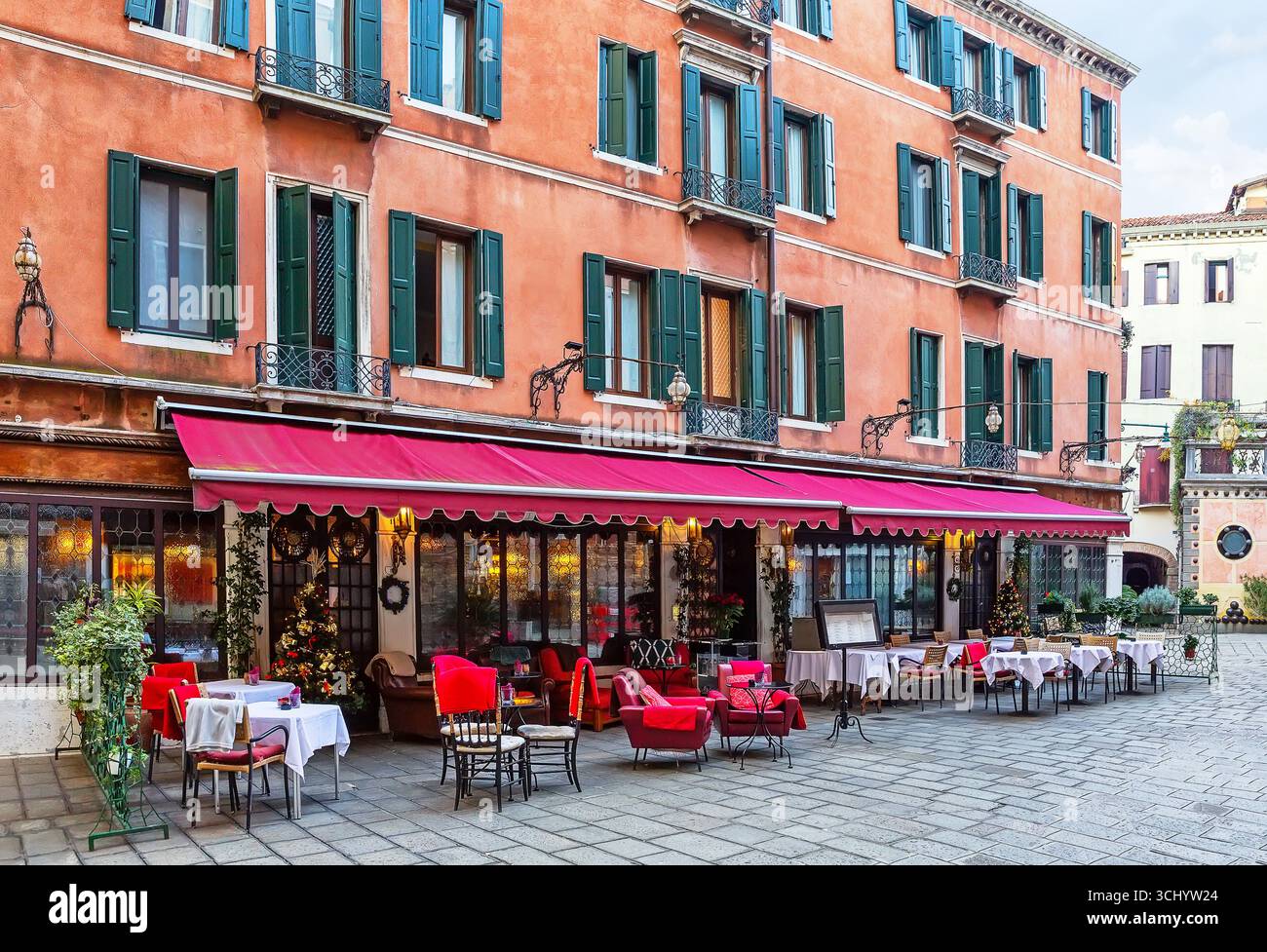 Farbenfrohe alte Straße mit Tischen des Restaurants in Venedig, Italien. Architektur und Wahrzeichen von Venedig. Gemütliches Stadtbild von Venedig. Stockfoto