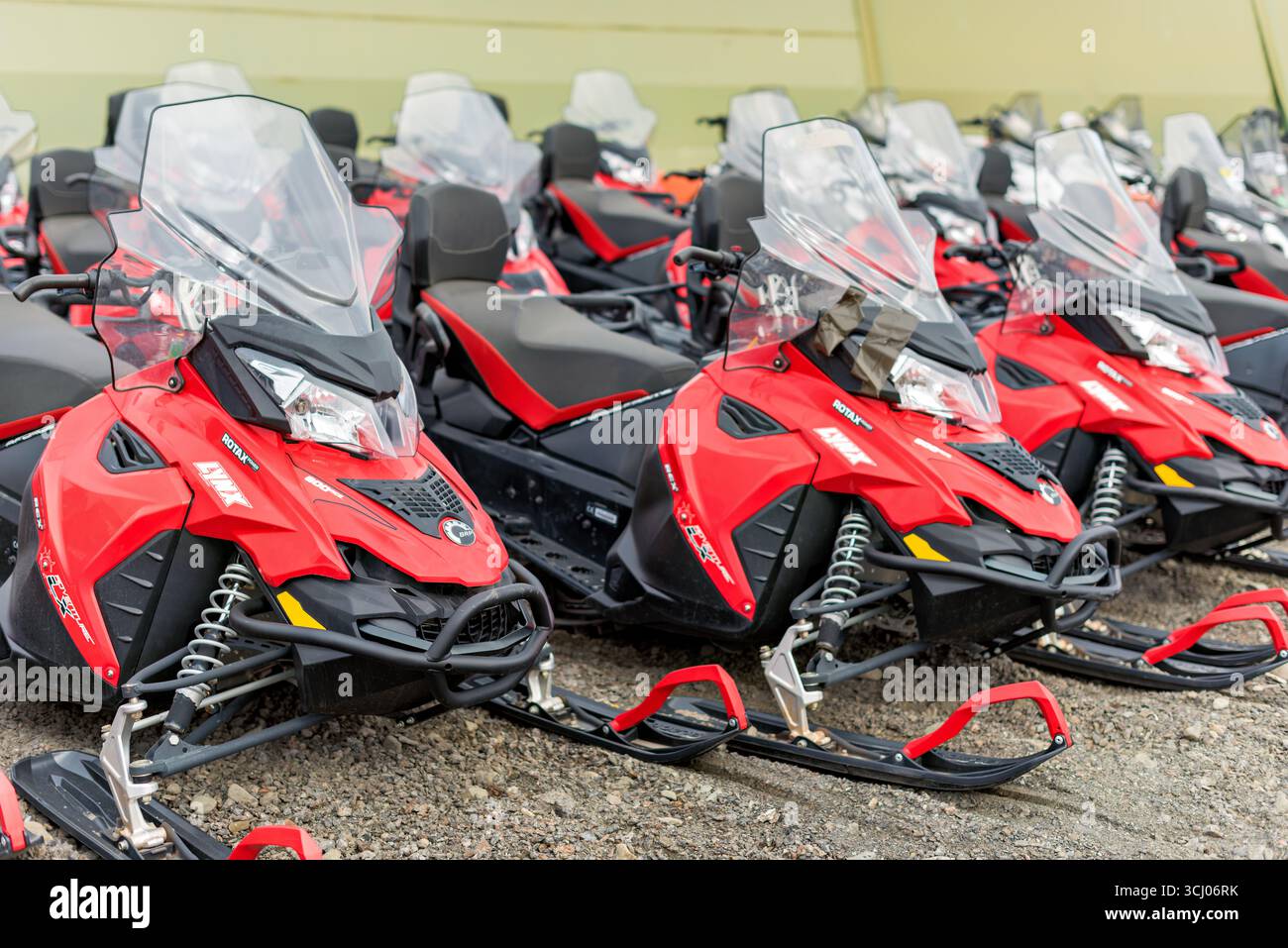 Rote Schneemobile in Longyearbyen Svalbard // LONGYEARBYEN, Svalbard und Jan Mayen — Eine Linie roter und schwarzer Lynx 600 ACE Adventure REX Schneemobile steht auf einem Kiesboden. Diese Schneemobile sind mit Rotax-Motoren ausgestattet, die für ihre Leistung und Zuverlässigkeit bei kaltem Wetter bekannt sind. Die Marke Lynx ist für ihr robustes Design bekannt, das sich für abenteuerliche Expeditionen in anspruchsvollem Gelände eignet. Das Adventure REX-Modell wurde speziell für Entdeckungen und Touren entwickelt und bietet Komfort und Leistung. Longyearbyen, das Verwaltungszentrum von Svalbard, ist ein Tor zur Arcti Stockfoto