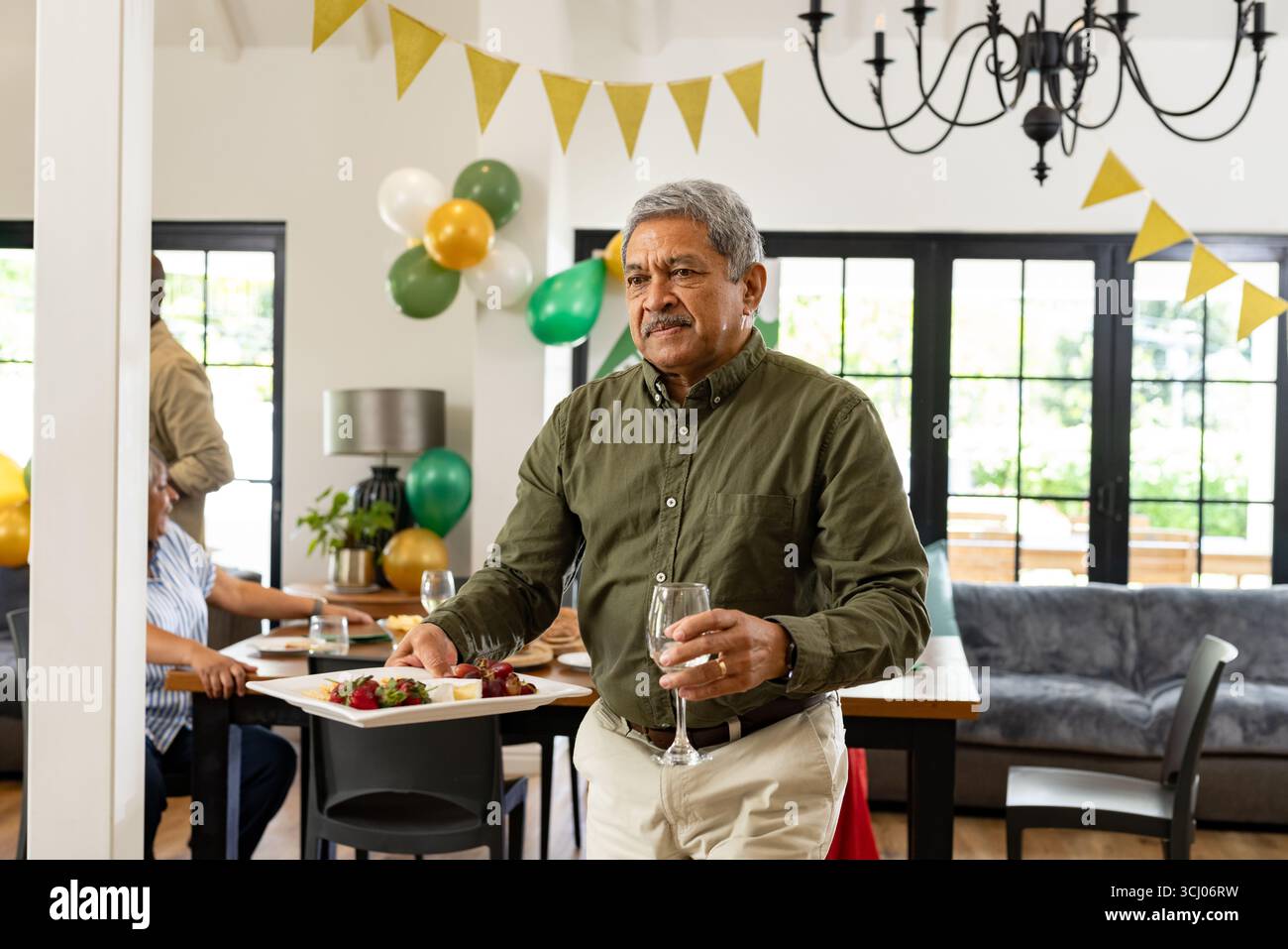 Mann, der Essen und Getränke auf der Heimfeier trägt, sieht fröhlich und einladend aus Stockfoto