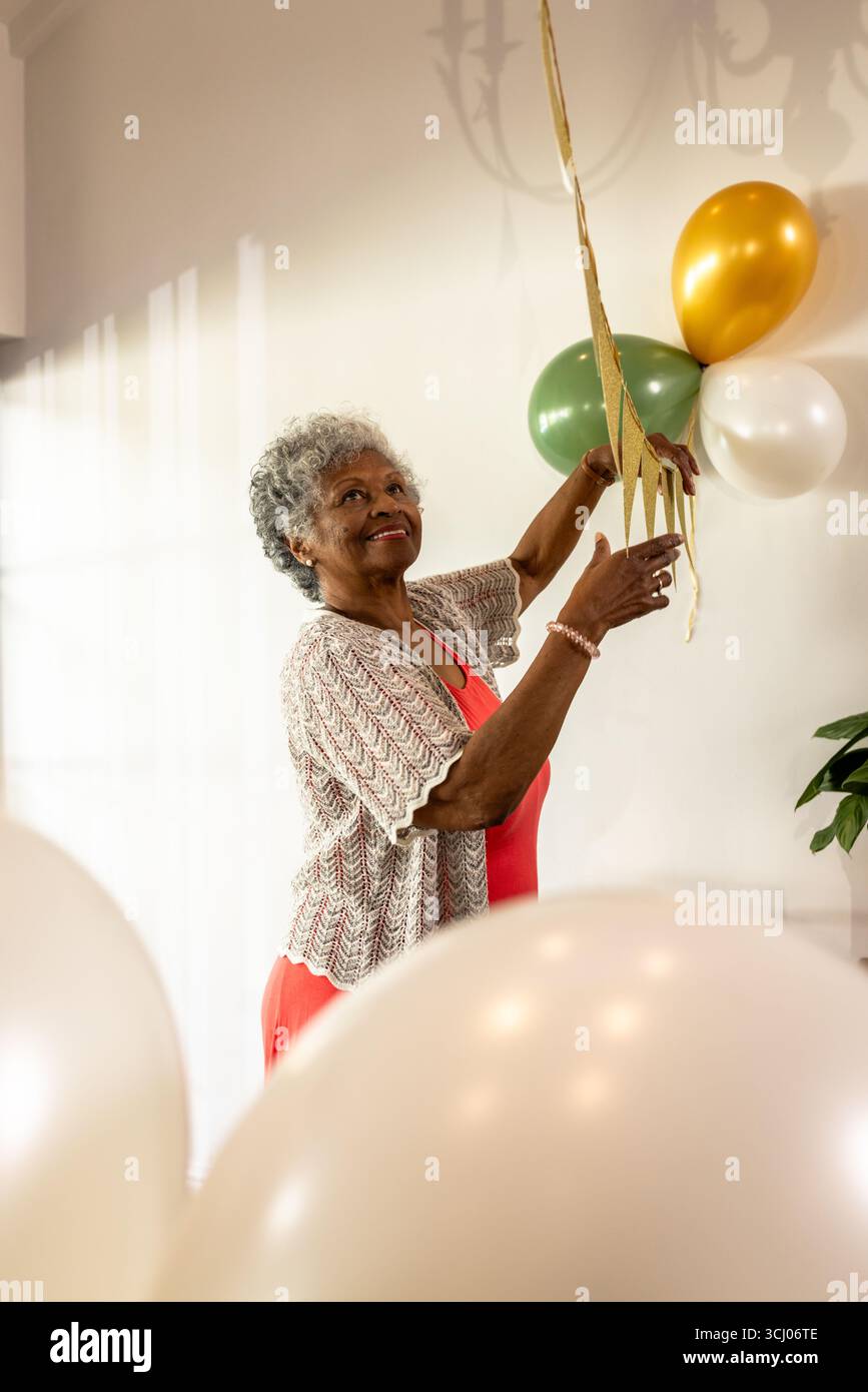 Mit Ballons dekorieren, Seniorin lächelt während der Party, zu Hause Stockfoto