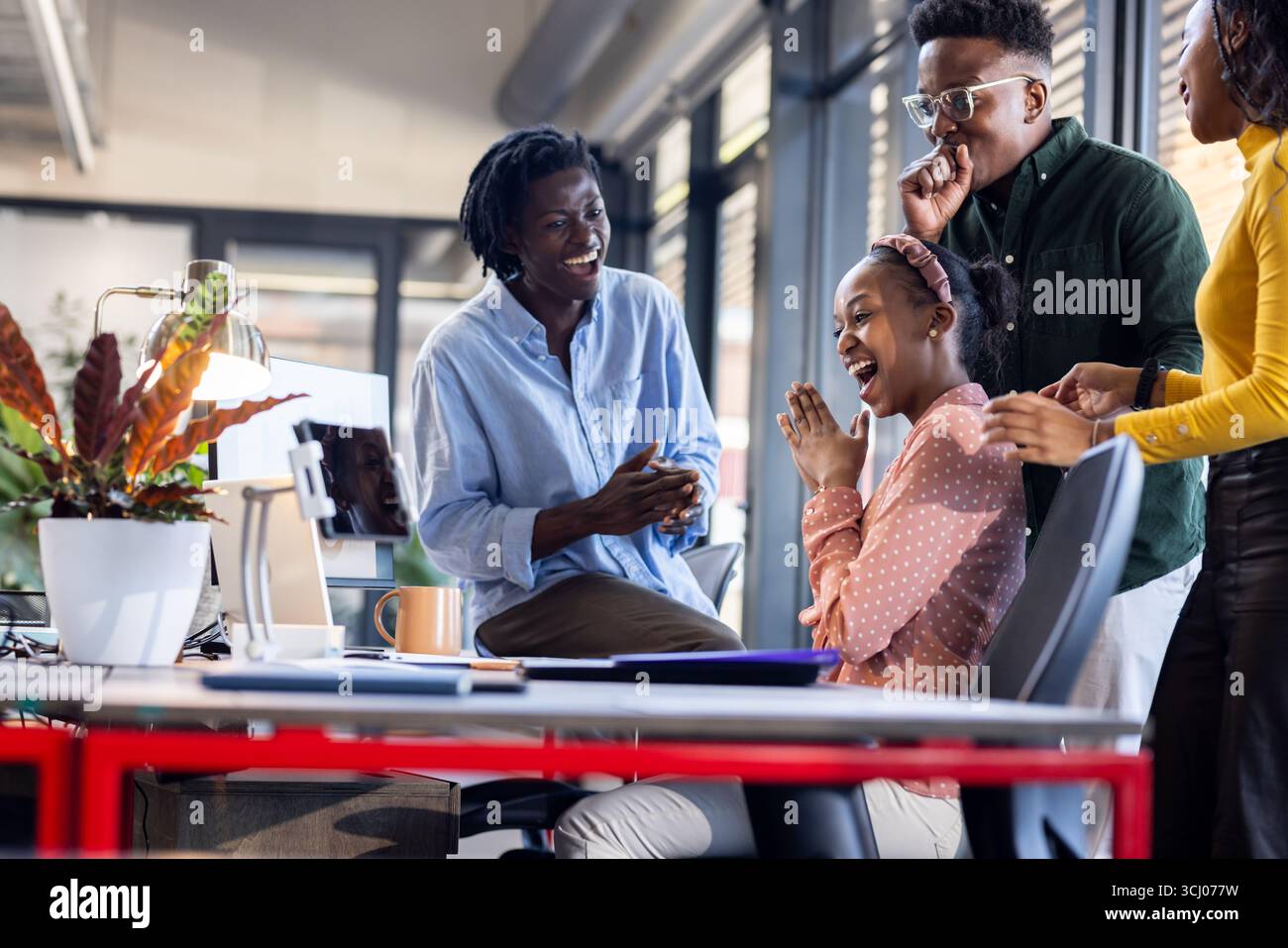 Afroamerikanische Kollegen lachen und arbeiten in einer modernen Büroumgebung zusammen Stockfoto
