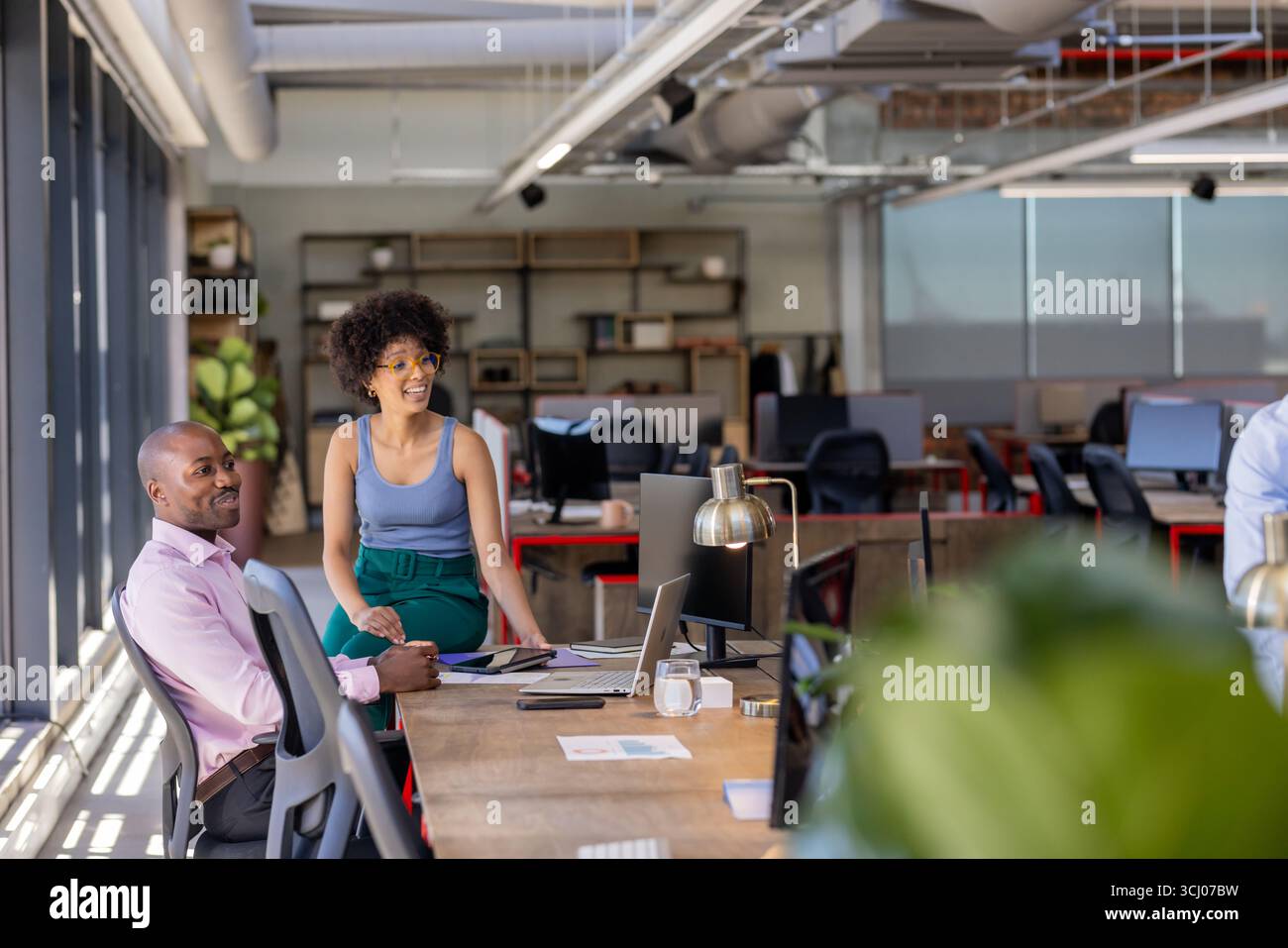 Kollegen, die am modernen Bürotisch zusammenarbeiten und Projekte mit Begeisterung diskutieren Stockfoto