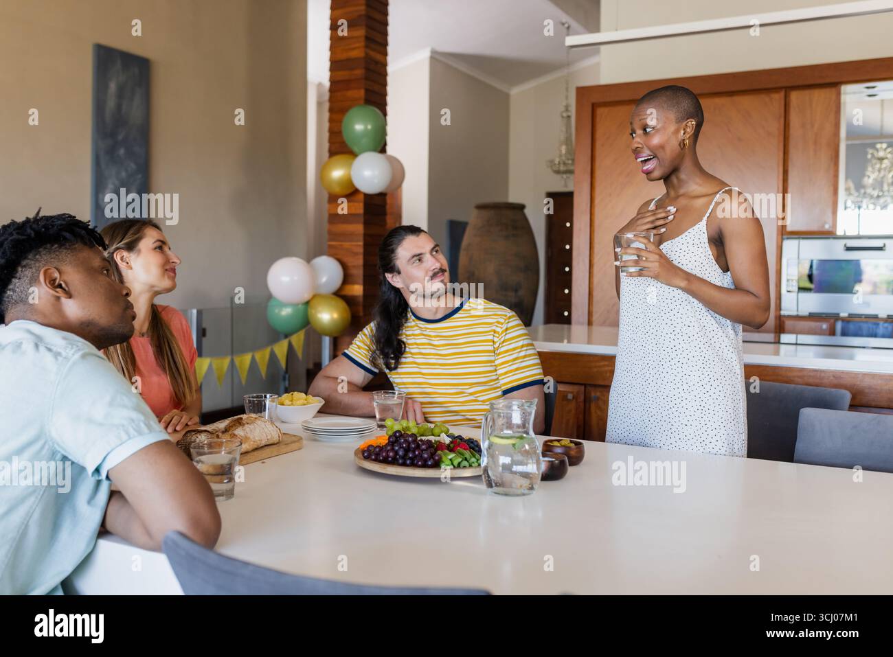 Freunde, die sich am Esstisch mit frischem Obst und Getränken unterhalten Stockfoto