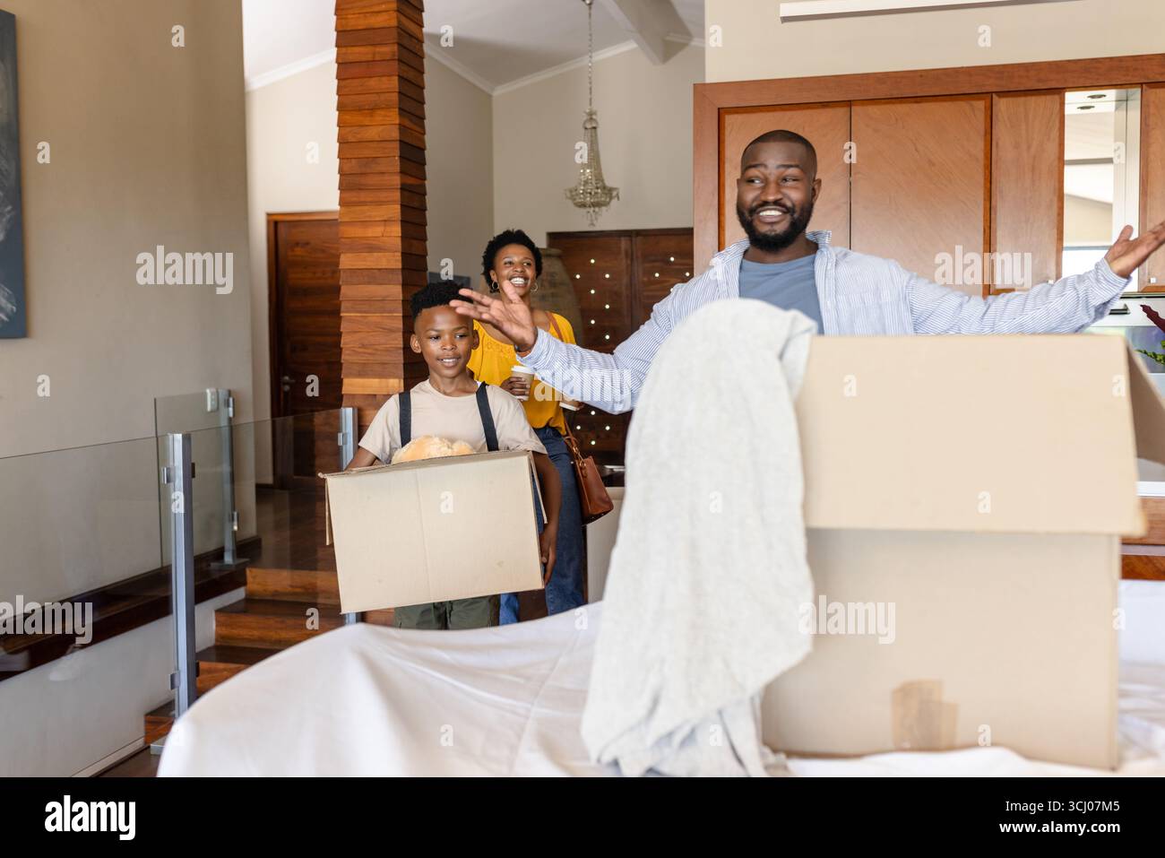 Die Familie packt Kartons in einem neuen Zuhause aus, lächelt und genießt einen Neuanfang Stockfoto