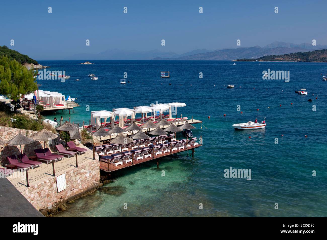 Pontile di prolungamento della spiaggia proteso sull'acqua limpida a Ksamil Stockfoto