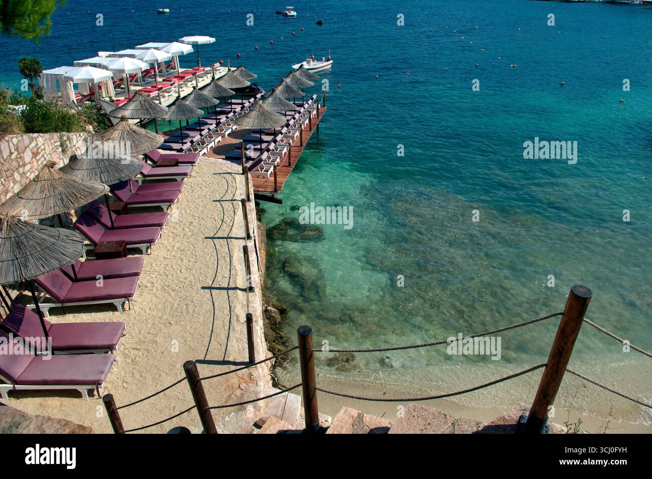 Pontile di prolungamento della spiaggia proteso sull'acqua limpida a Ksamil Stockfoto