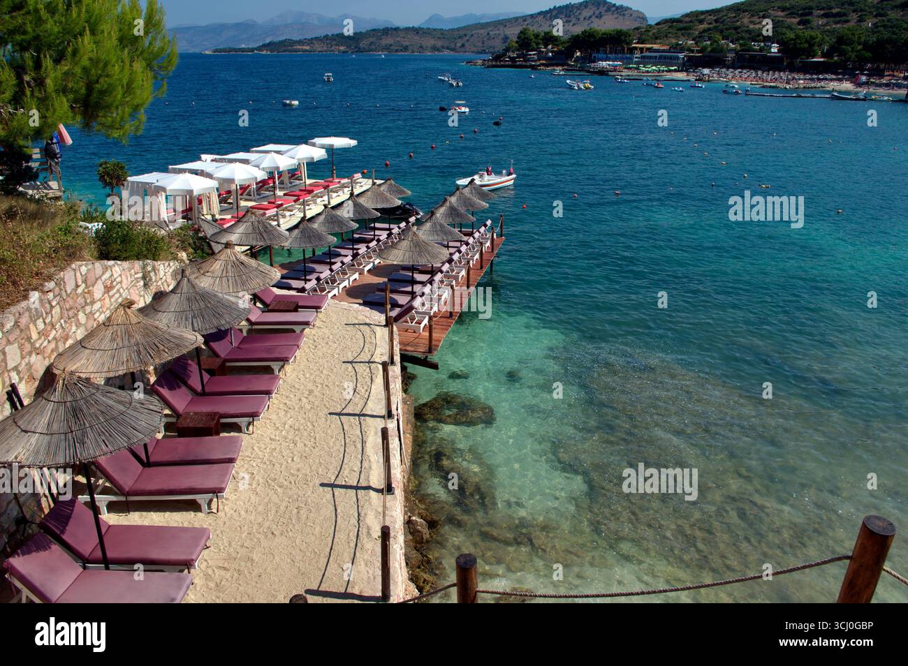 Pontile di prolungamento della spiaggia proteso sull'acqua limpida a Ksamil Stockfoto
