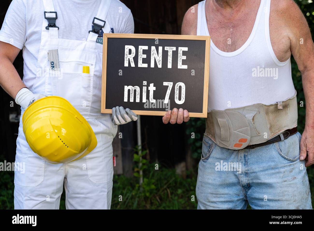 Deutschland - 4. September 2025: FOTOMONTAGE, zwei Bauarbeiterauszubildende Senior halten mit 70 Jahren einen Vorzeichenausscheidungsgrad. Ein älterer Mann trägt einen Stützgürtel für seinen verletzten Rücken. Das Bild zeigt, wie fragwürdig die körperliche Belastung im Alter ist. *** FOTOMONTAGE, zwei Bauarbeiter AZUBI Senior halten eine Tafel mit der Aufschrift Rente mit 70. Alterer Mann mit Stützgürtel für den kaputten Rücken. Das Motiv macht deutlich, wie fraglich körperliche Arbeit Belastung bis ins hohe Alter ist. Stockfoto