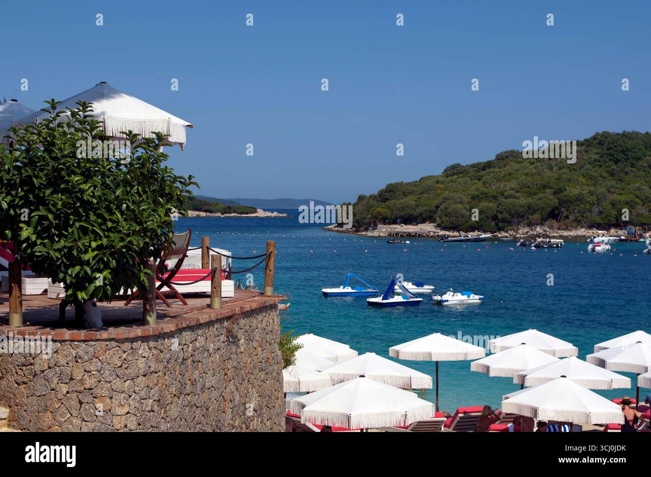 Ombrelloni su una spiaggetta di Ksamil contro il Mare trasparente ed azzurro Stockfoto