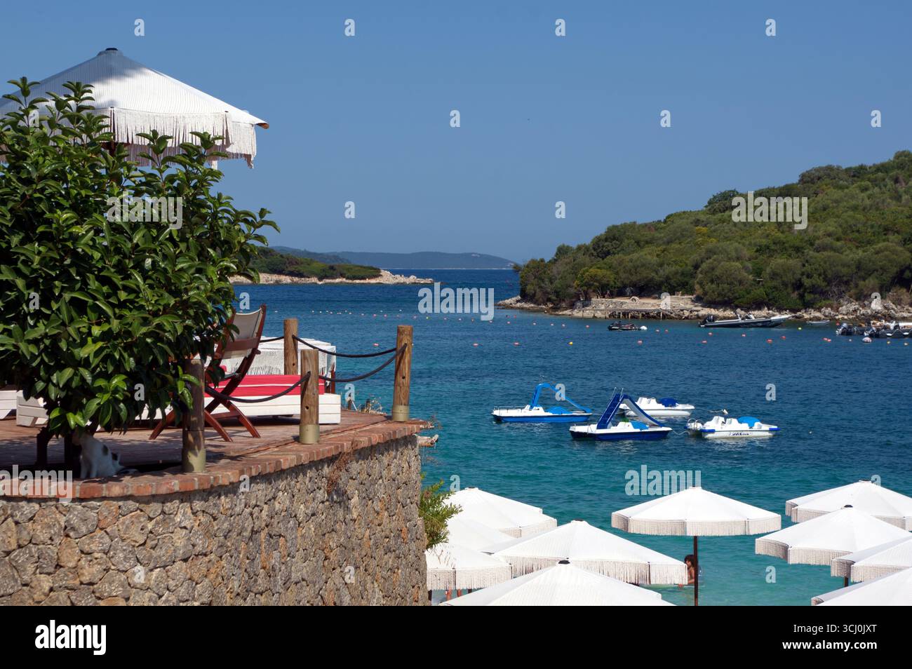 Ombrelloni su una spiaggetta di Ksamil contro il Mare trasparente ed azzurro Stockfoto