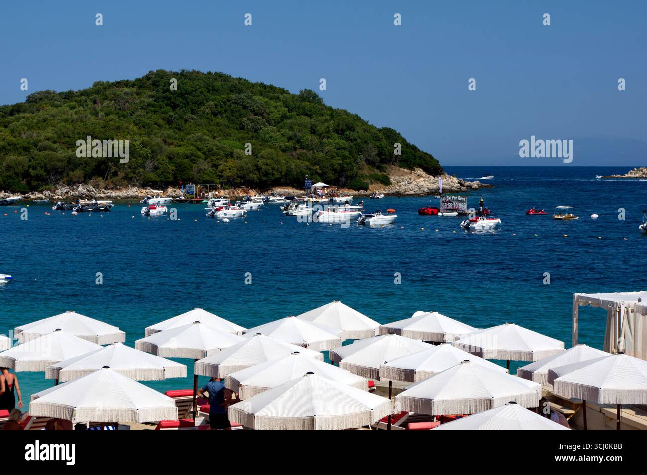 Panoramica di una spiaggetta a Ksamil complete amente occupata da ombrelloni e lettini e del Mare azzurro alle spalle Stockfoto