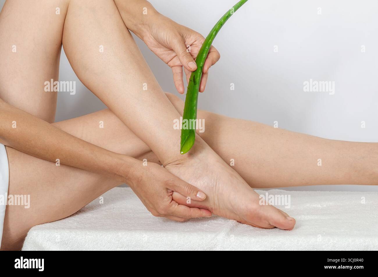 Die Frau verwendet Saft aus grünem Aloe Vera Blatt, um die Haut der Fersen mit Feuchtigkeit zu versorgen. Konzept der natürlichen Selbstpflege und Hautfeuchtigkeit, Heilung. Stockfoto