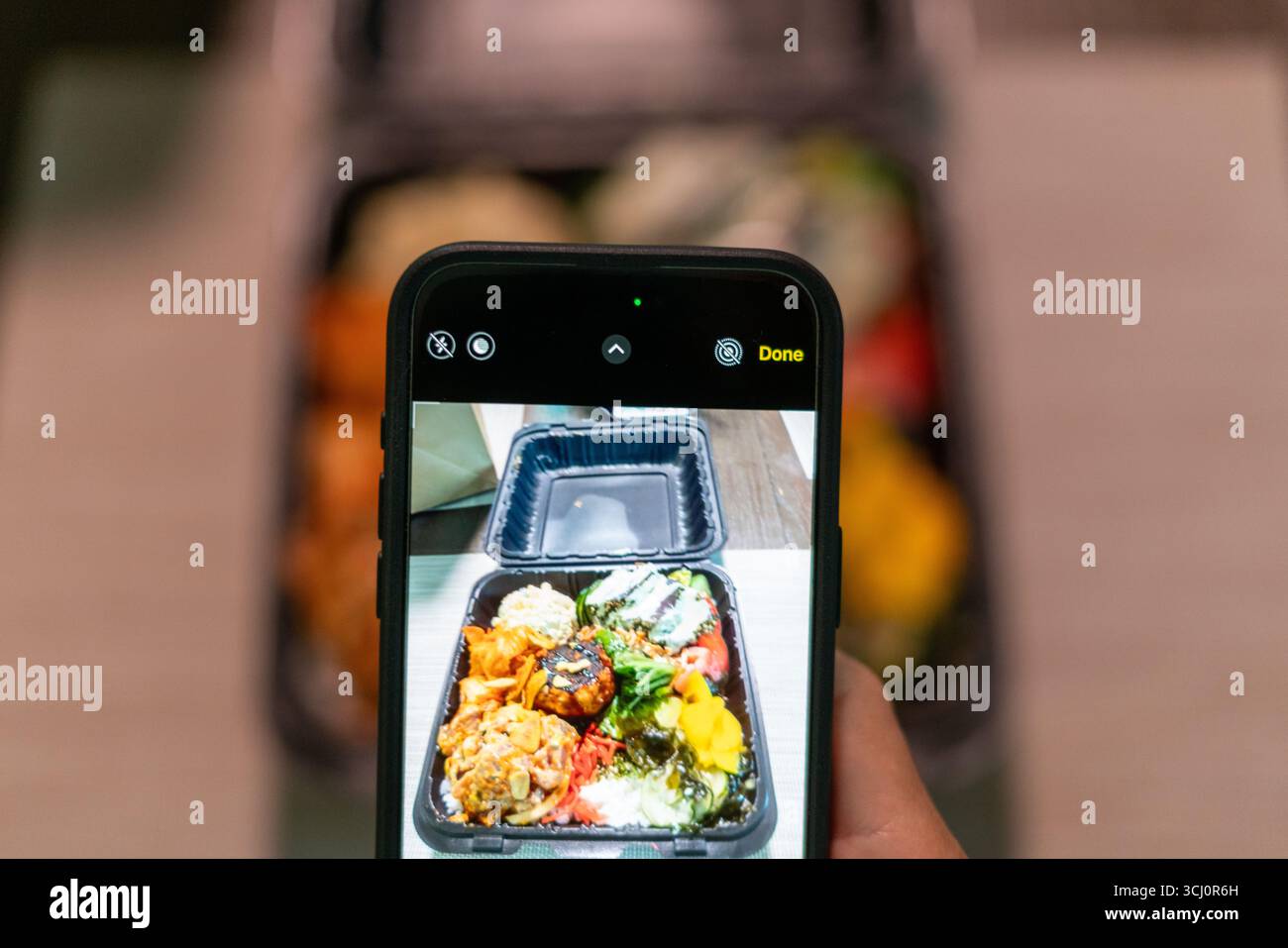 Black man’s Hand macht Fotos von ahi Poke Bowl mit Smartphone und hebt die digitale Kultur, hawaiianische Küche und die technologische Verbindung mit Lebensmitteln hervor Stockfoto