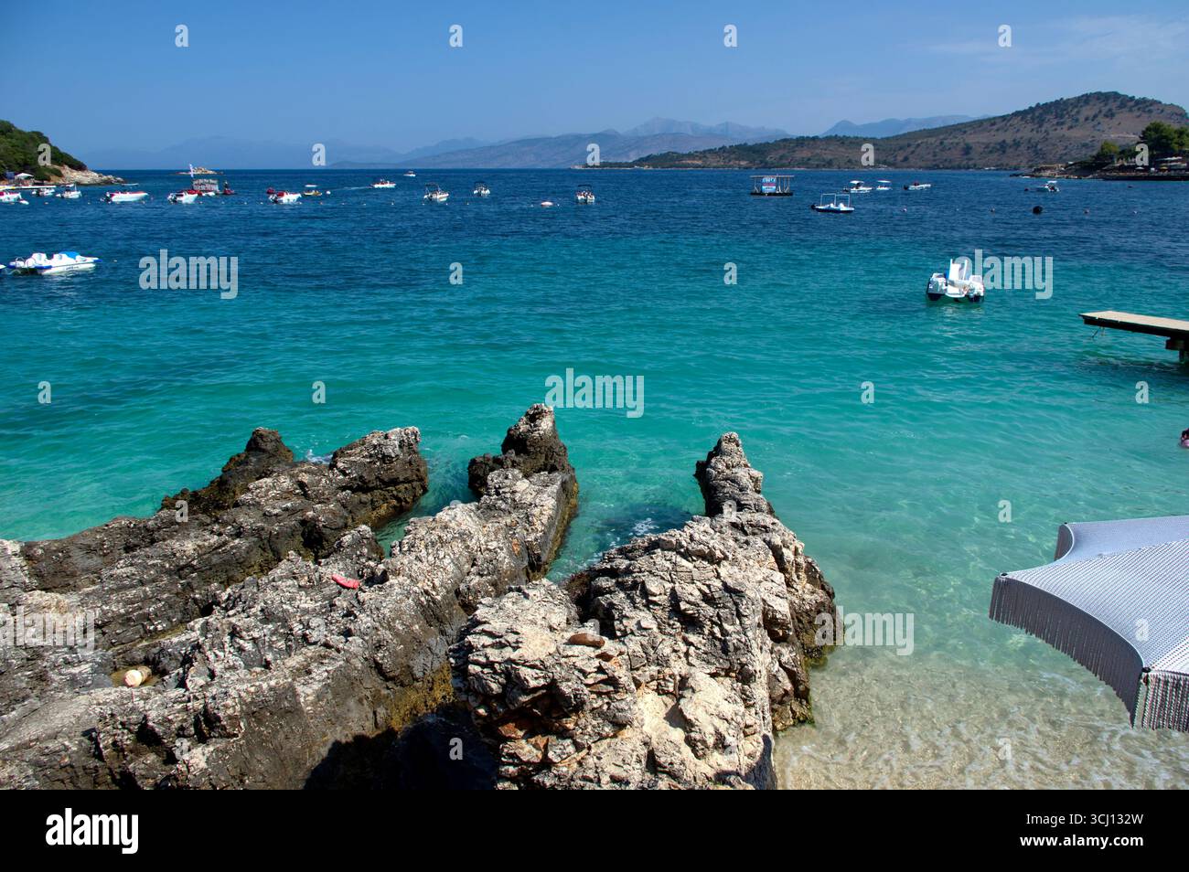Ombrellone accanto ad uno scoglio in una spiaggia di Ksamil Stockfoto