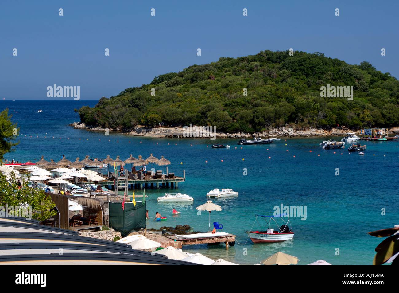 Panoramica di una spiaggetta a Ksamil complete amente occupata da ombrelloni e lettini e del Mare azzurro alle spalle Stockfoto