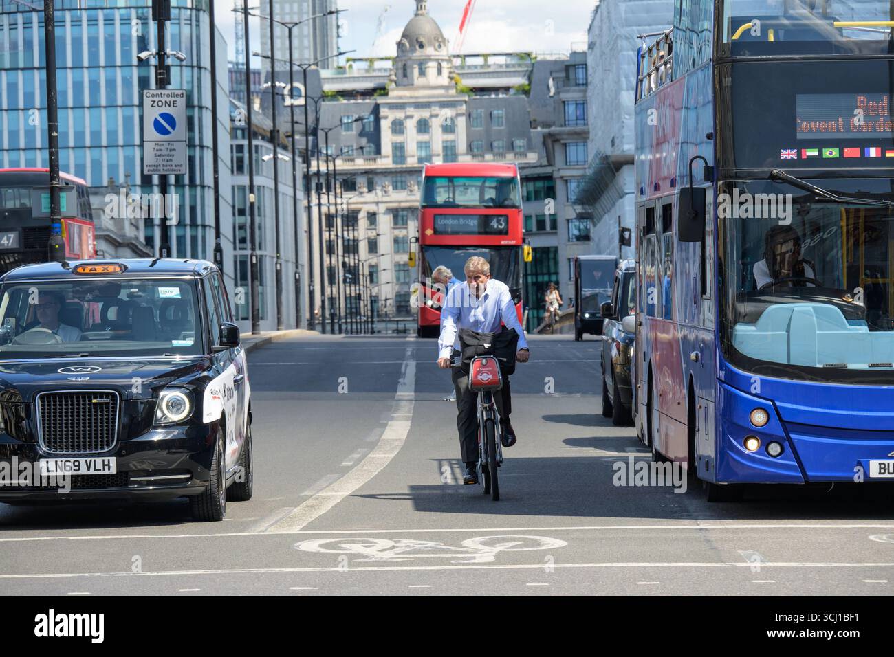 London, Großbritannien. Schwarzes Londoner Taxi, Red London Doppeldecker, ein Touristenbus mit offenem Oberdeck und ein Radfahrer auf einem Santander Leihfahrrad auf der London Bridge Stockfoto