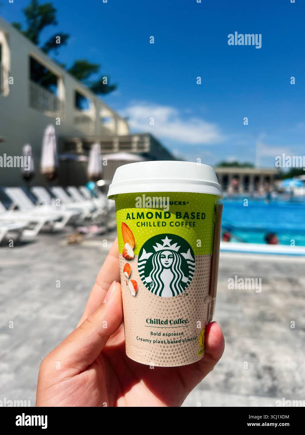 Solotvyno, Ukraine - 30. Juni 2025: Starbucks-Getränk mit Mandelmilch, im Freien am Pool vor einer sonnigen Terrasse. Stockfoto
