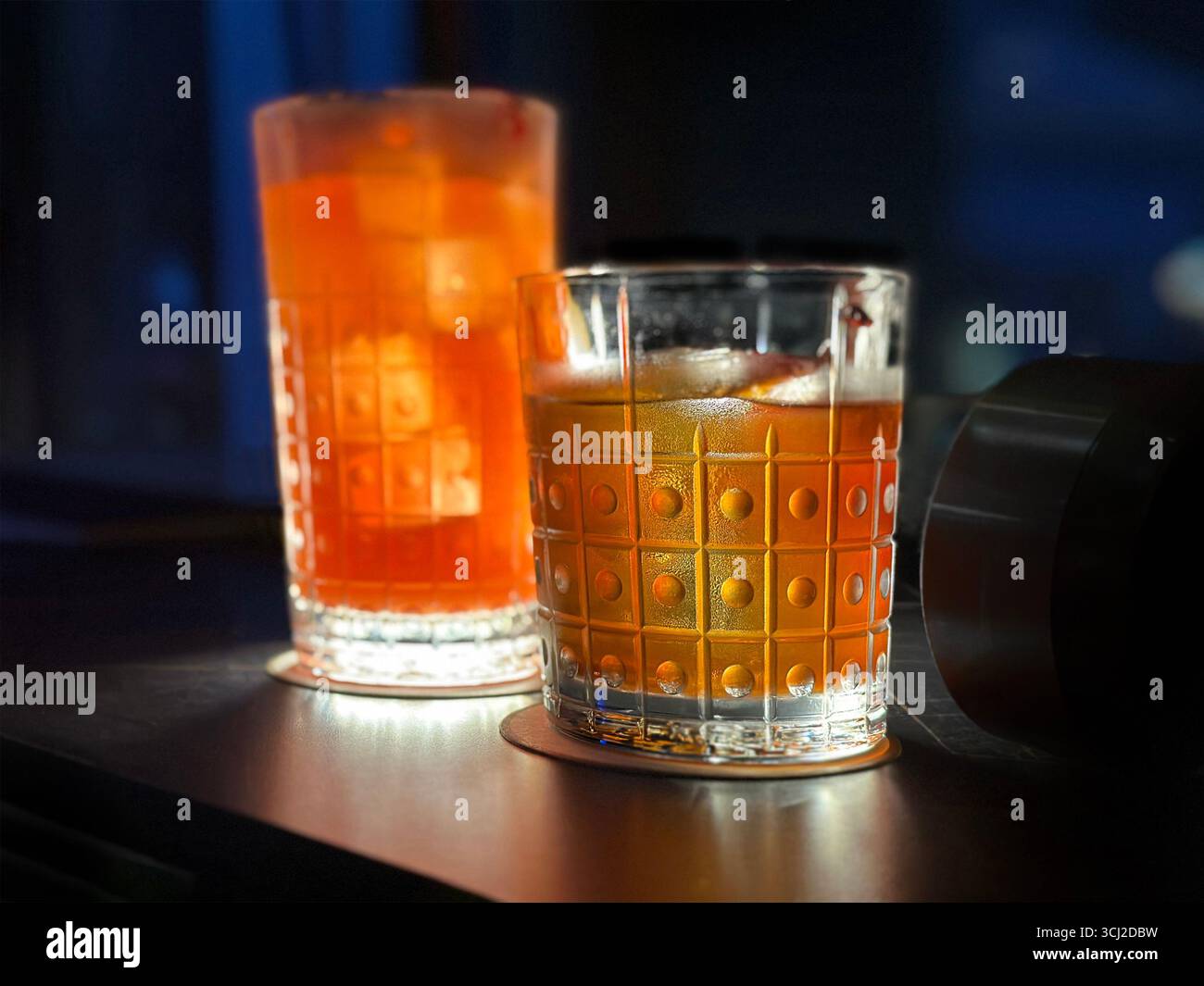 Nahaufnahme von 2 Cocktails Singapore Sling & Old Fashioned in gemusterten Gläsern, schummrig beleuchtete Tische, Atmosphäre des Singapore Atico Lounge & Bar ION Orchard Stockfoto