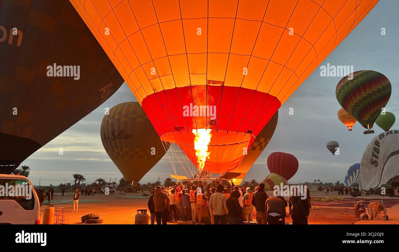 Luxor, Ägypten - 10. Februar 2025: Heißluftballons werden bei Sonnenaufgang mit Luft gefüllt, um einen Flug über Luxor, Ägypten, vorzubereiten. Stockfoto