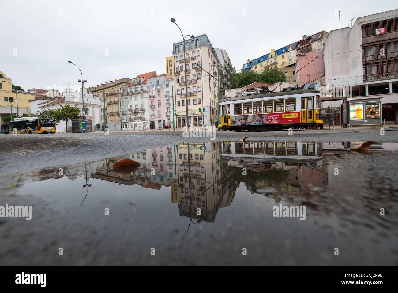 Eine atemberaubende Straßenaufnahme in Lissabon, Portugal, mit einer klassischen gelben Straßenbahn und einer Reihe von bunten Gebäuden. Die gesamte Szene wird in einem dargestellt Stockfoto