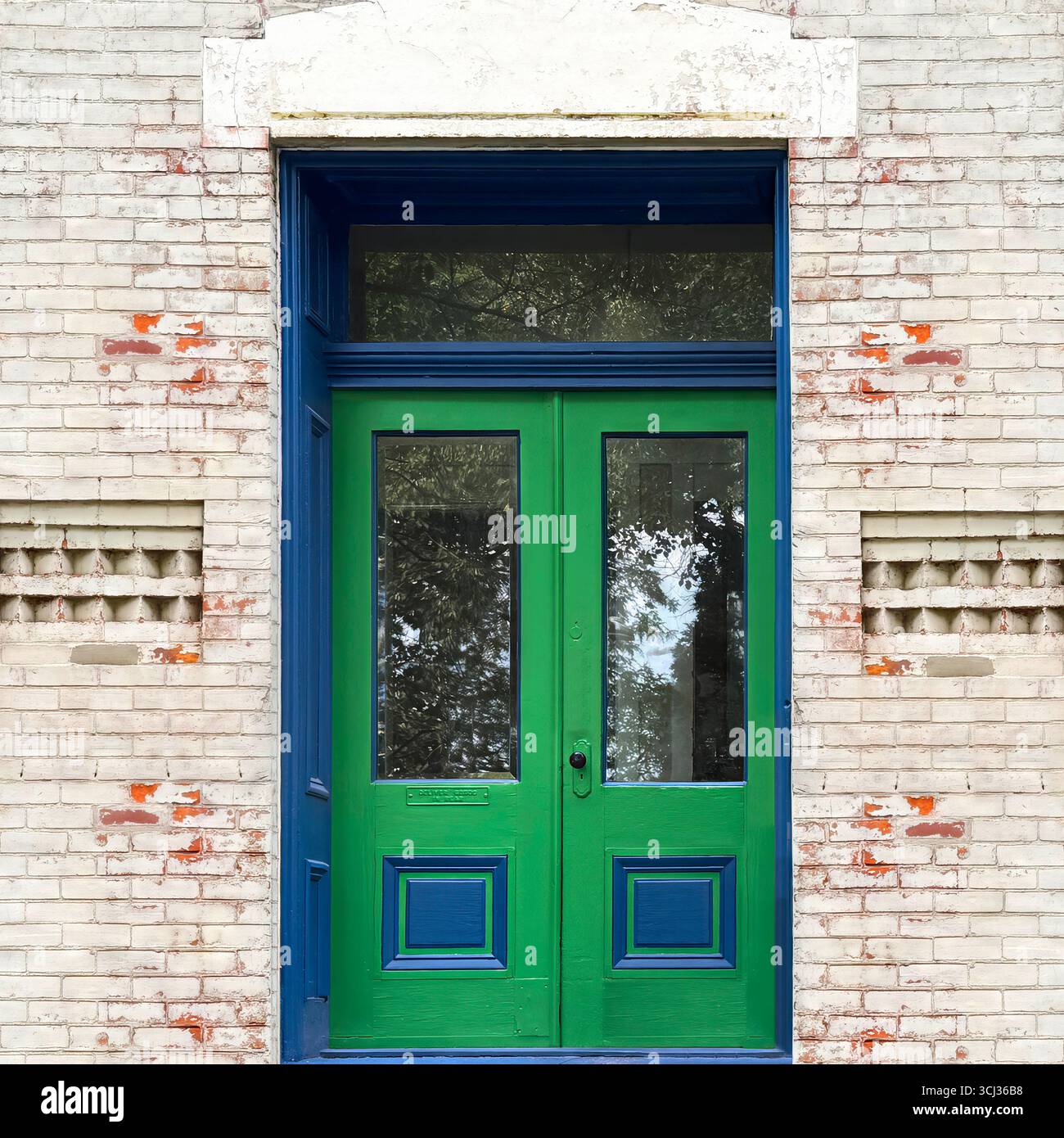 Hellgrüne Doppeltür mit blauer Zierleiste in einer verwitterten Ziegelfassade, historische Stadtarchitektur in Chicago. Stockfoto