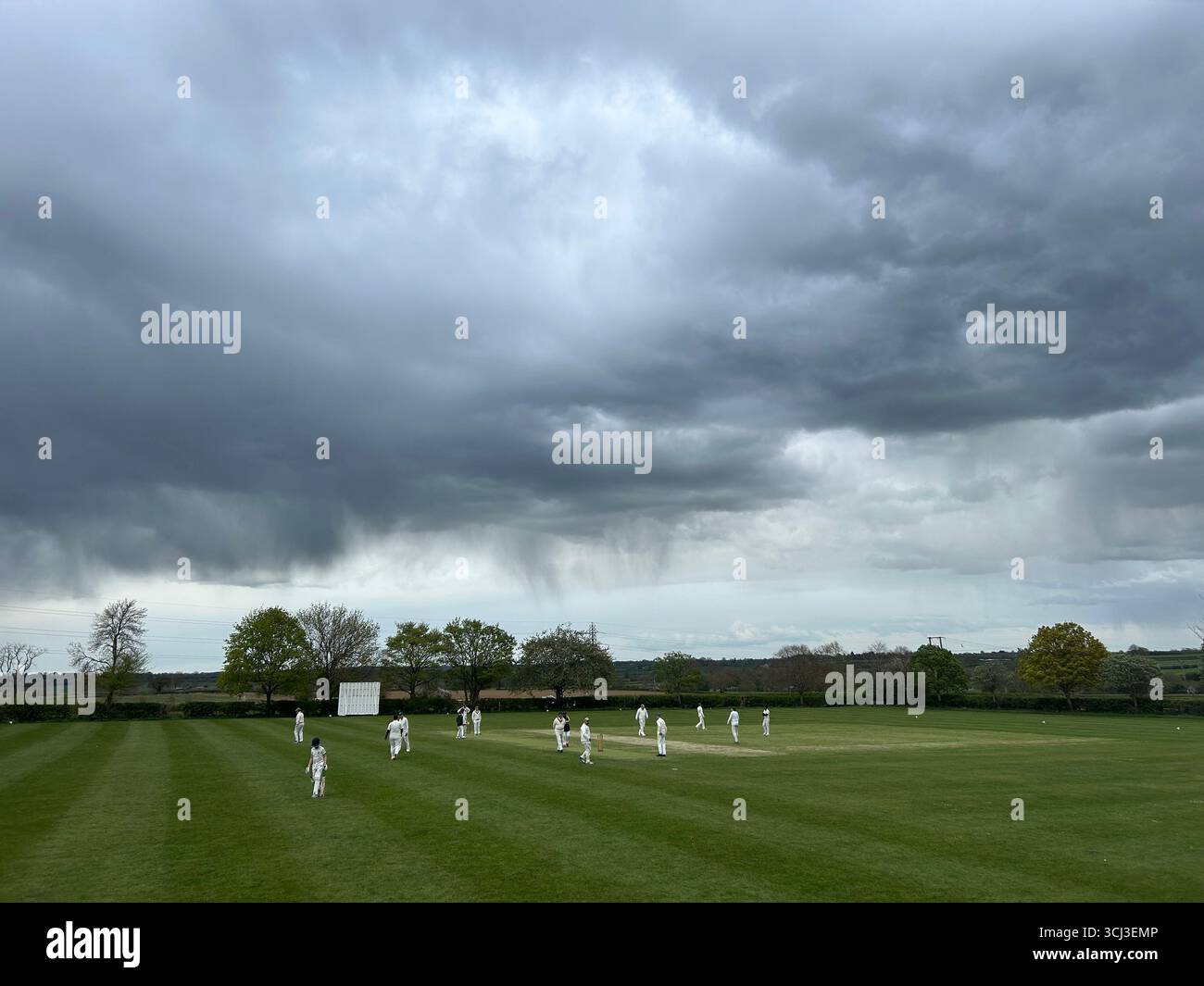 Sturmwolken über einem malerischen englischen Cricket-Spiel in Leicestershire, Großbritannien - Smartphone-aufgenommenes Stockfoto
