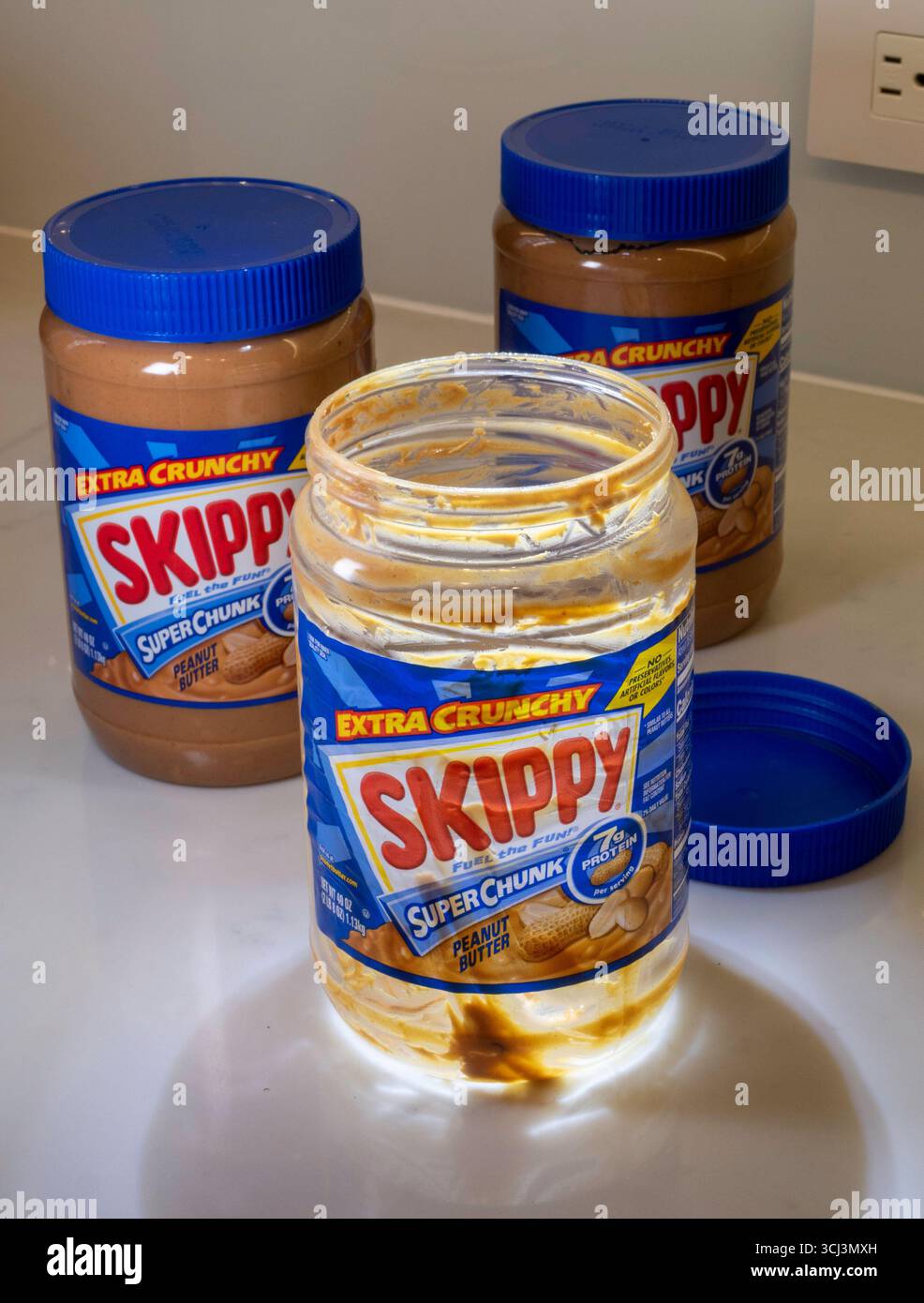 Stillleben von drei Gläsern Skippy Erdnussbutter, zwei neue ungeöffnete, eine leere, 2025, USA Stockfoto
