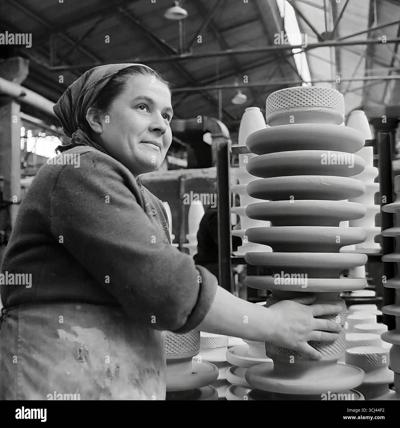 Eine erfahrene sowjetische Arbeiterin mit inspiriertem Gesicht inspiziert Ende der 1950er Jahre in einer Werkstatt im Werk Sloviansk fertige Isolatoren Das Archivporträt eines Arbeiterveteranen im Stil des sozialistischen Realismus vermittelt ein Gefühl der würde und des Glaubens an eine glänzende Zukunft. Dieses Bild einer Weise arbeitenden Frau ist ein Symbol für die kreative Kraft und das friedliche Leben des Donbas und fängt die verlorene Ära vor dem Krieg ein Stockfoto