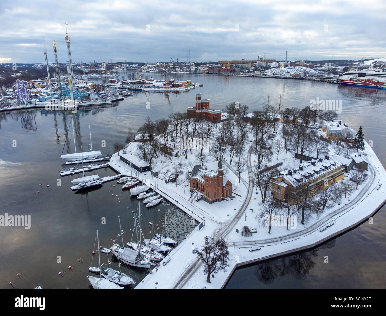 Aus der Vogelperspektive auf die schneebedeckte Insel Kastellholmen, mit dem berühmten Vergnügungspark Gröna Lund in der Ferne, Stockholm County, Schweden. Stockfoto