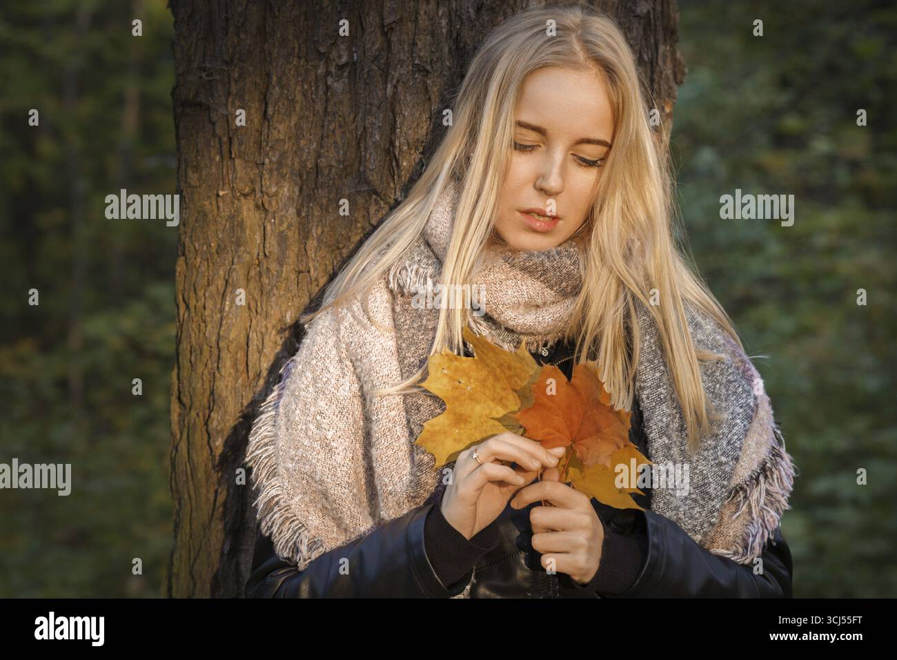 Trauriges Mädchen im Herbstpark mit Blättern, getöntem Bild Stockfoto