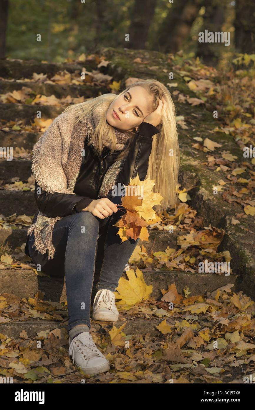 Trauriges Mädchen im Herbstpark sitzend, gedämpftes Bild Stockfoto Trauriges Mädchen im Herbstpark sitzend, gedämpftes Bild Stockfoto