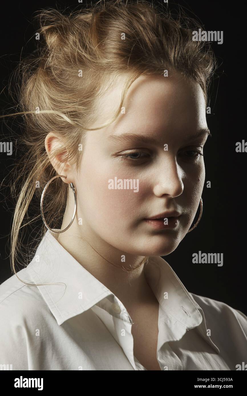 Junge, traurige, schöne Frau, die auf schwarzem Hintergrund wegschaut Stockfoto