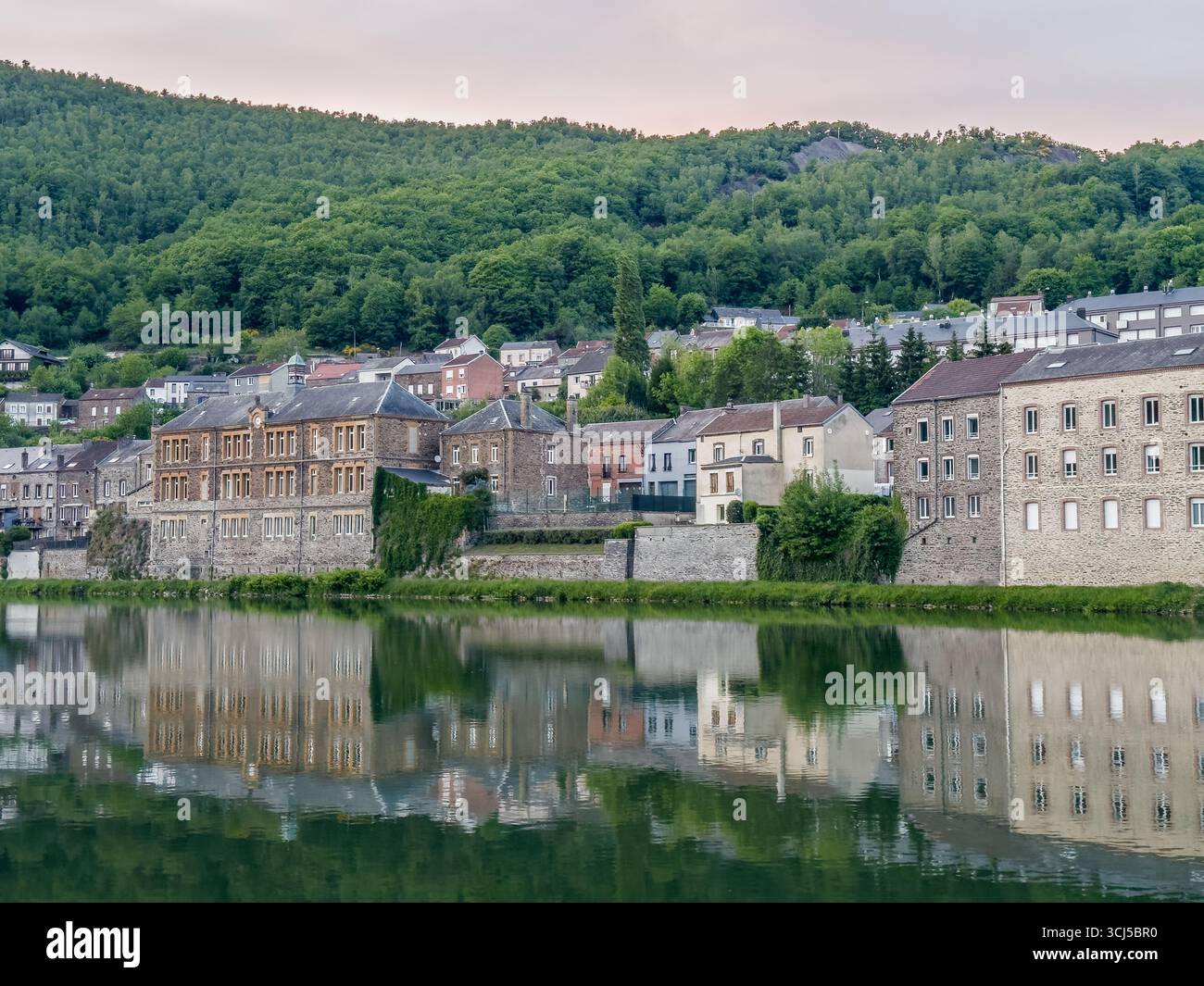 Charmante Häuser säumen die maas in Montherme, deren Reflexionen eine malerische Szene schaffen Stockfoto
