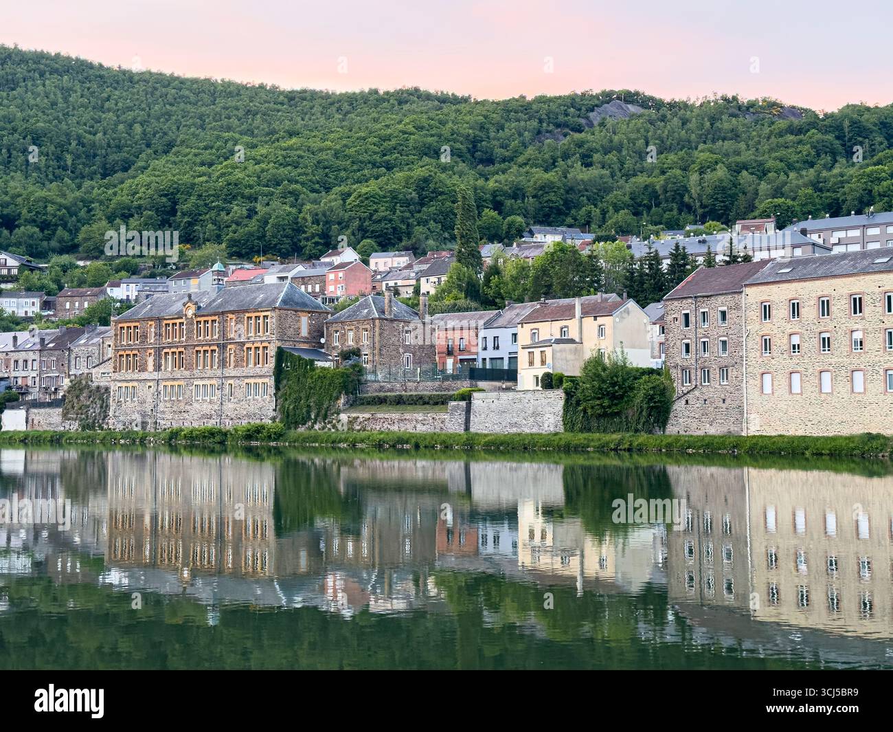 Bezaubernde Häuser, die sich auf der maas in einer kleinen französischen Stadt spiegeln und eine malerische Szene bei Sonnenuntergang schaffen Stockfoto