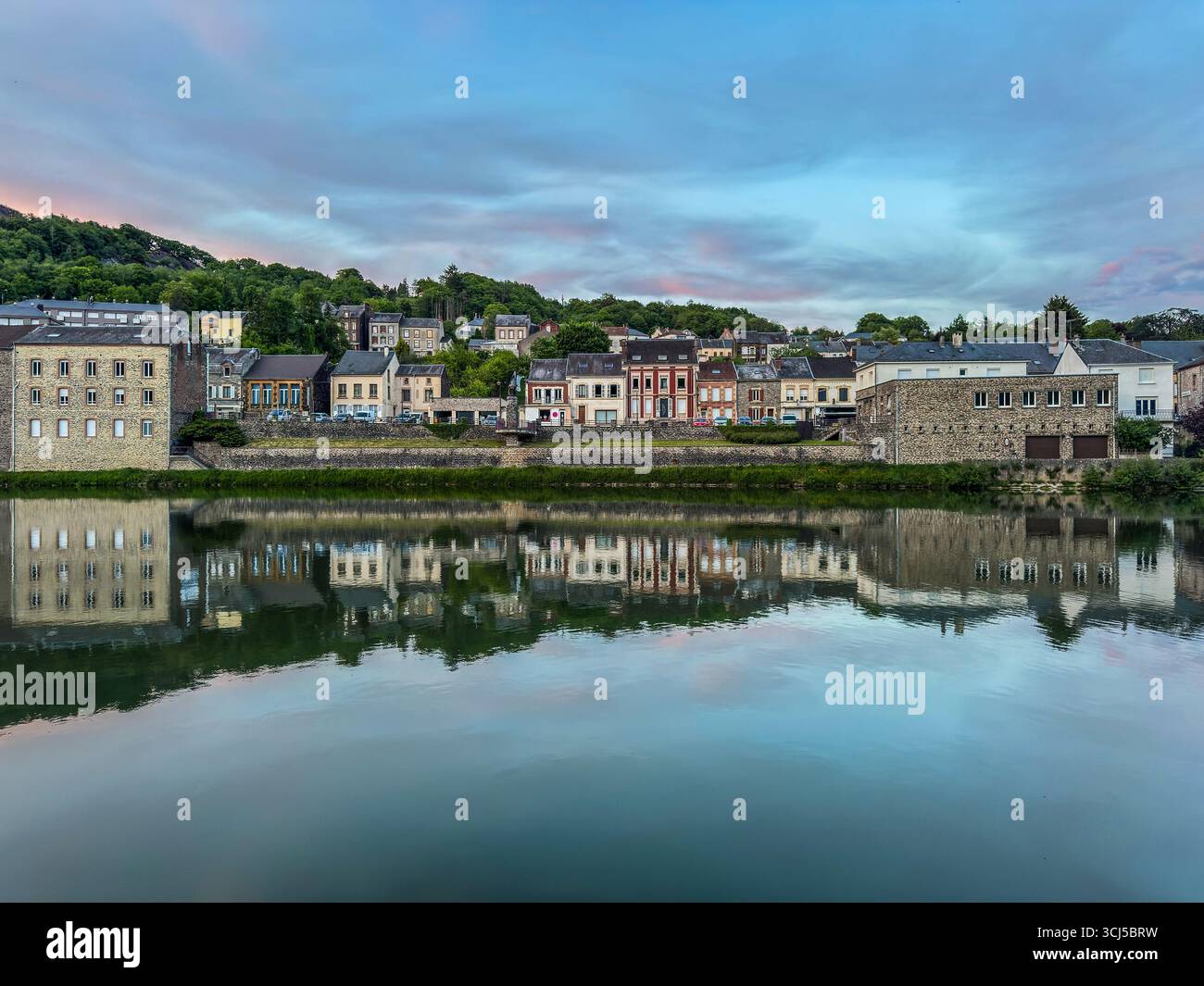 Häuser am Ufer spiegeln sich in der Abenddämmerung in der Wasseroberfläche und schaffen eine malerische Szene in einer kleinen französischen Stadt Stockfoto