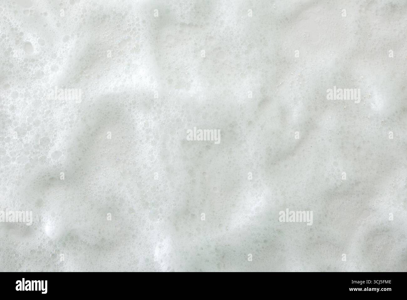Hintergrund mit Makro aus weißem, weichem, strukturiertem Seifenschaum mit vielen kleinen Blasen. Draufsicht. Stockfoto