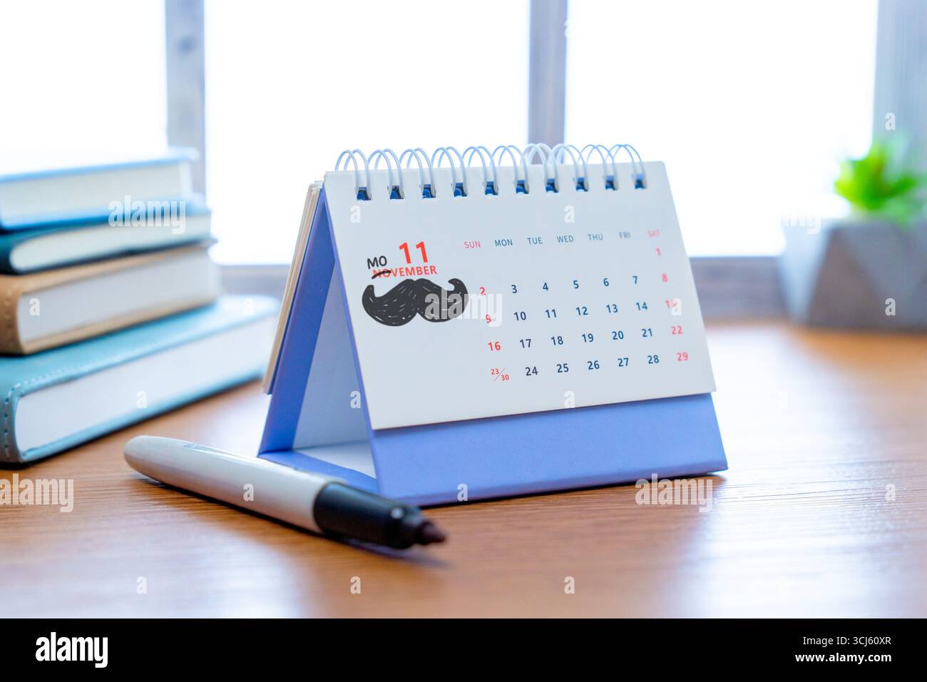 Ein Kalender, der bis zum Monat November geöffnet ist, mit einem schwarzen Hand gezeichneten Schnurrbart, der die Movember-Kampagne für die Gesundheit der Männer symbolisiert. Stockfoto