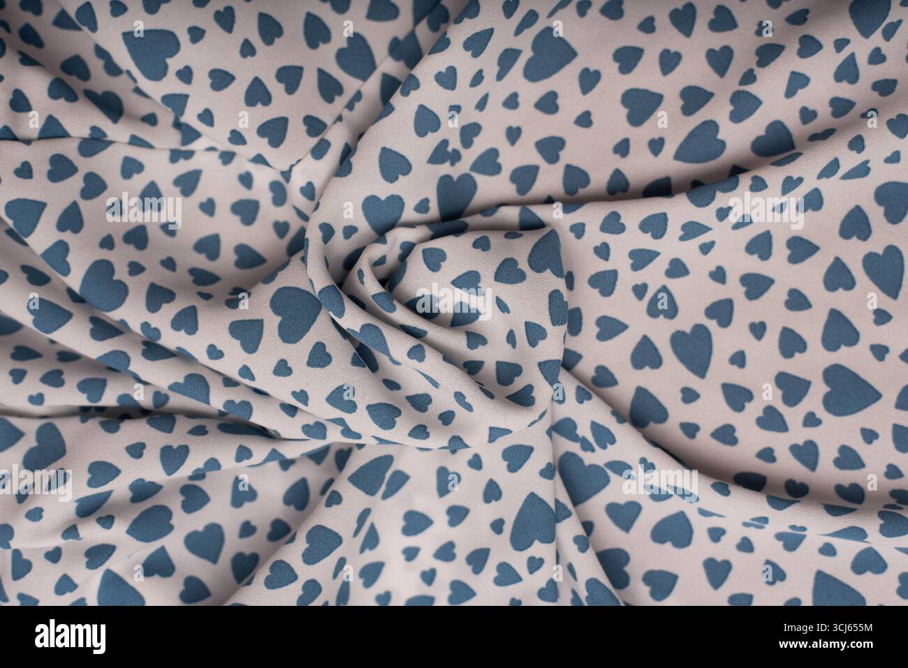 Weicher Stoff mit einem bezaubernden Muster aus blauen Herzen vor einem hellen Hintergrund, ideal für Valentinstag-Themen, Nähprojekte oder kreatives Design Stockfoto