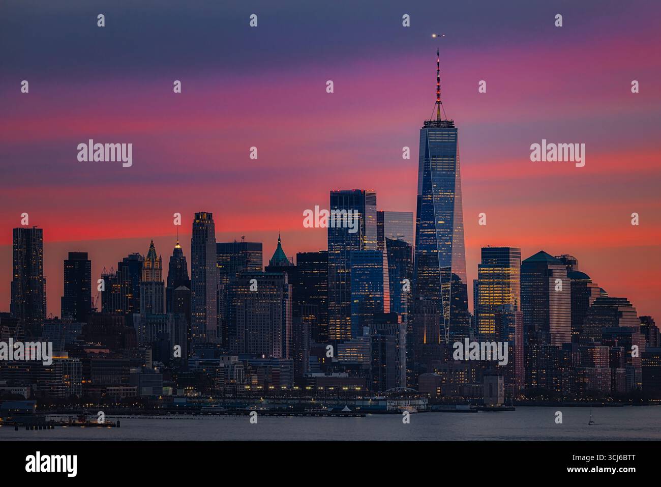 NYC Downtown Sunset – die Skyline von Lower Manhattan ist mit einem lebhaften Sonnenuntergang in Rosa- und Violettönen versehen. Stockfoto