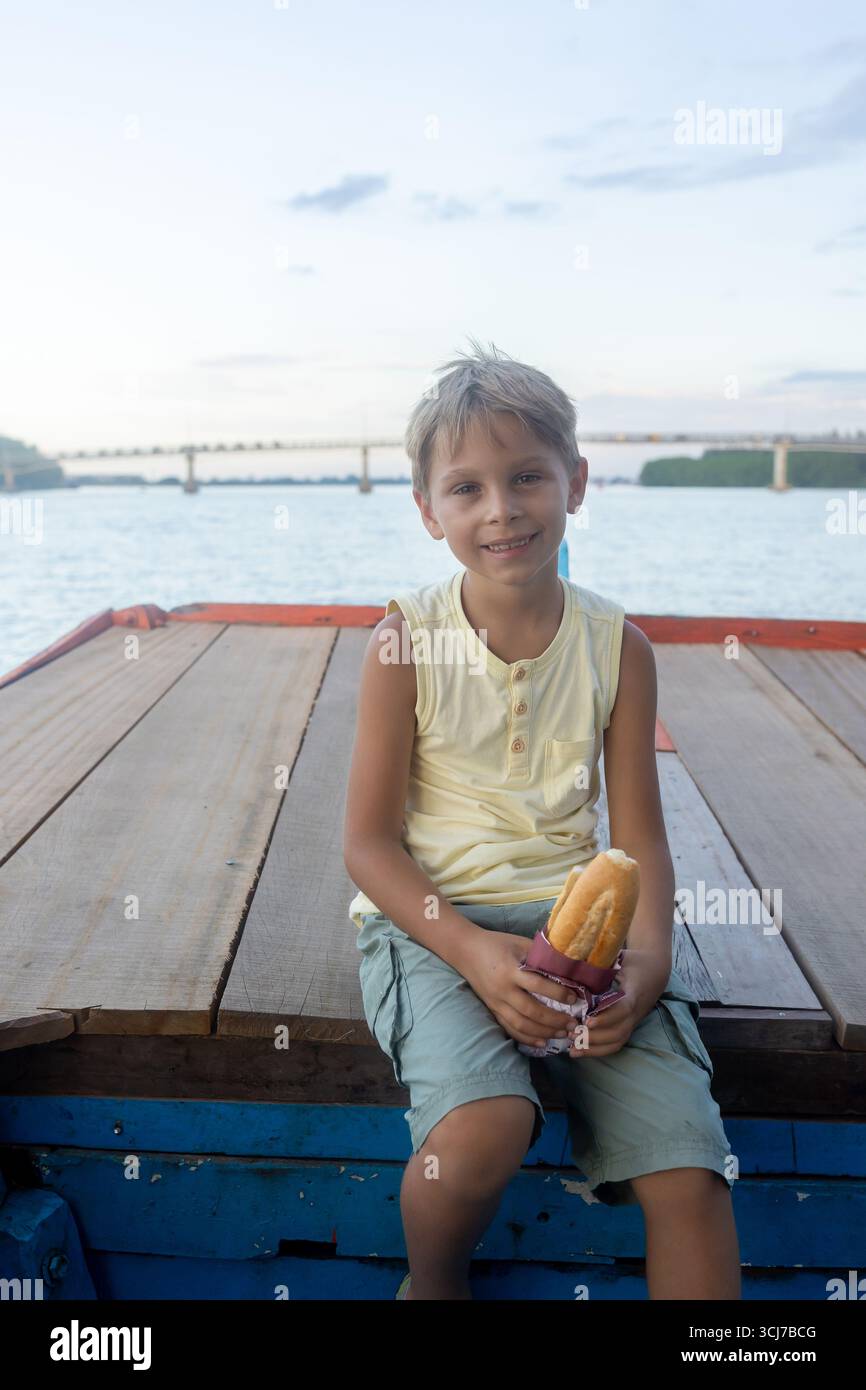Kind, isst Sandwich auf einer Bootsfahrt in Vietnam, im Sommer Stockfoto