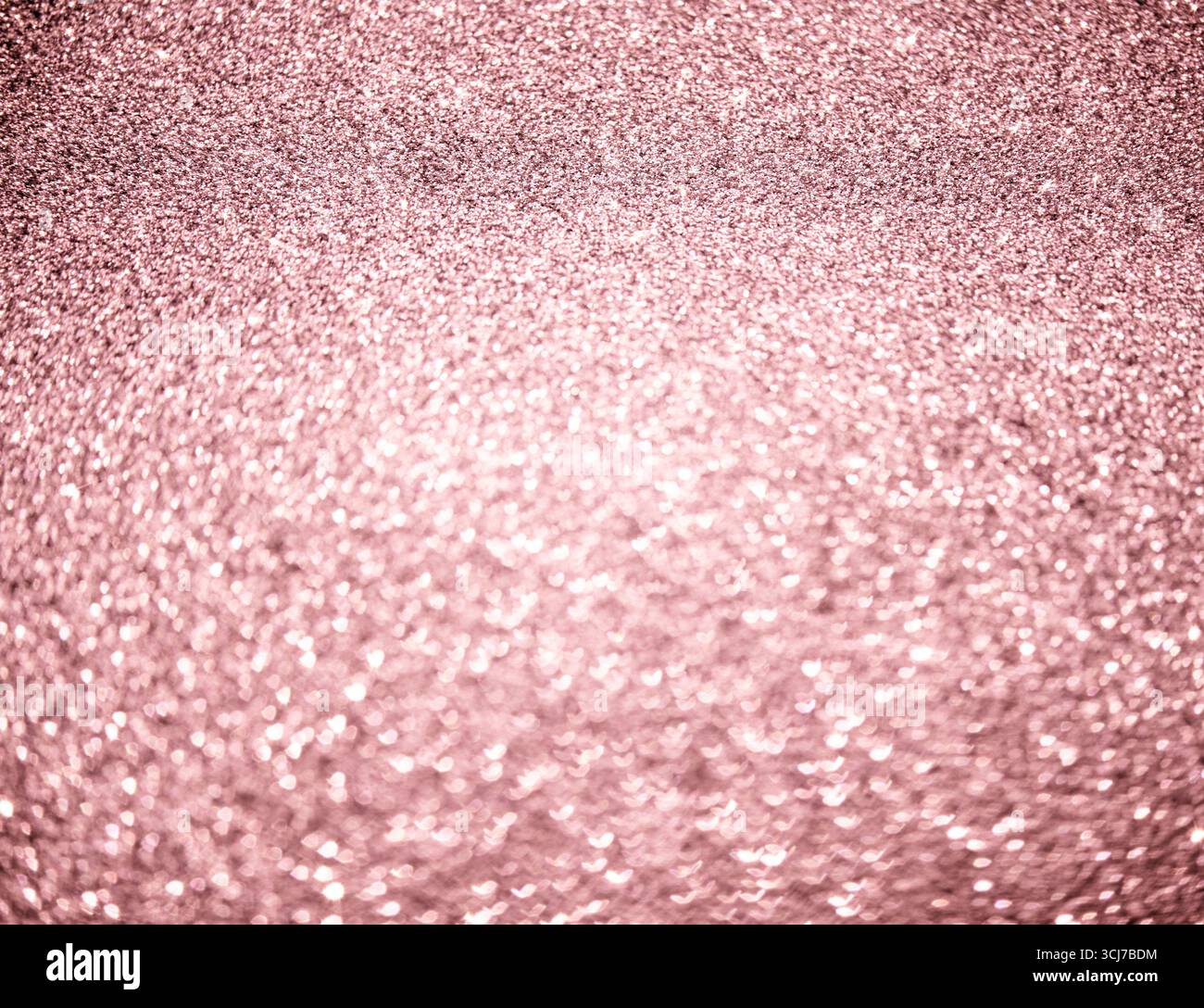 Elegante rosafarbene Glitzerstruktur mit funkelnden Highlights und weichem, verschwommenem Hintergrund, perfekt für festliche und feierliche Themen. Stockfoto