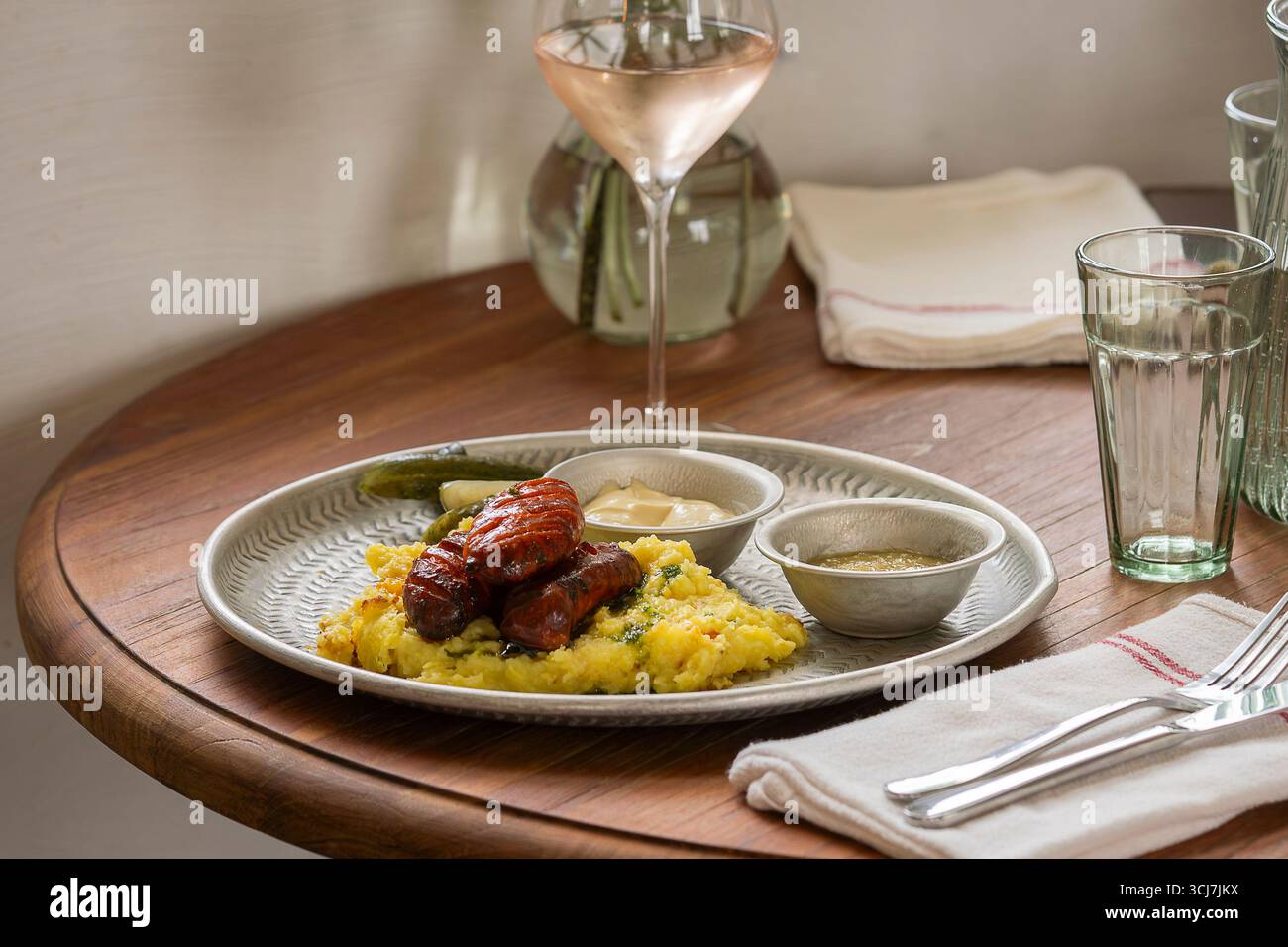 Gegrillte Würstchen mit Kartoffelpüree und Kräutern auf dem Tisch im Restaurant. Zwei Chorizo-Würstchen mit Kartoffelpüree. Stockfoto