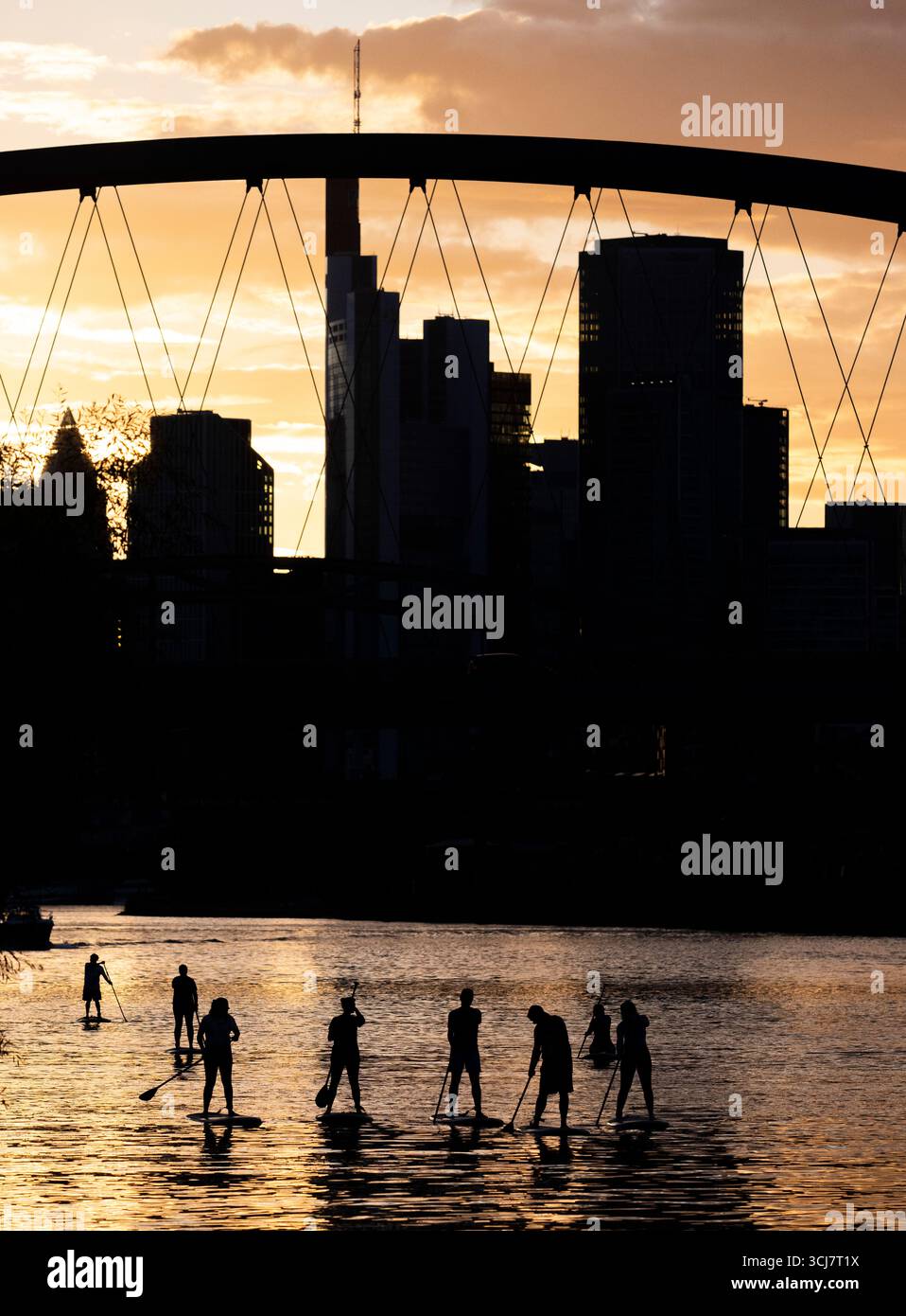 6. September 2025, Hessen, Frankfurt/Main: Mit Blick auf die Skyline im letzten Licht des Tages überqueren Stand-Up-Paddler den Main nahe der Osthafenbrücke. Foto: Boris Roessler/dpa Stockfoto