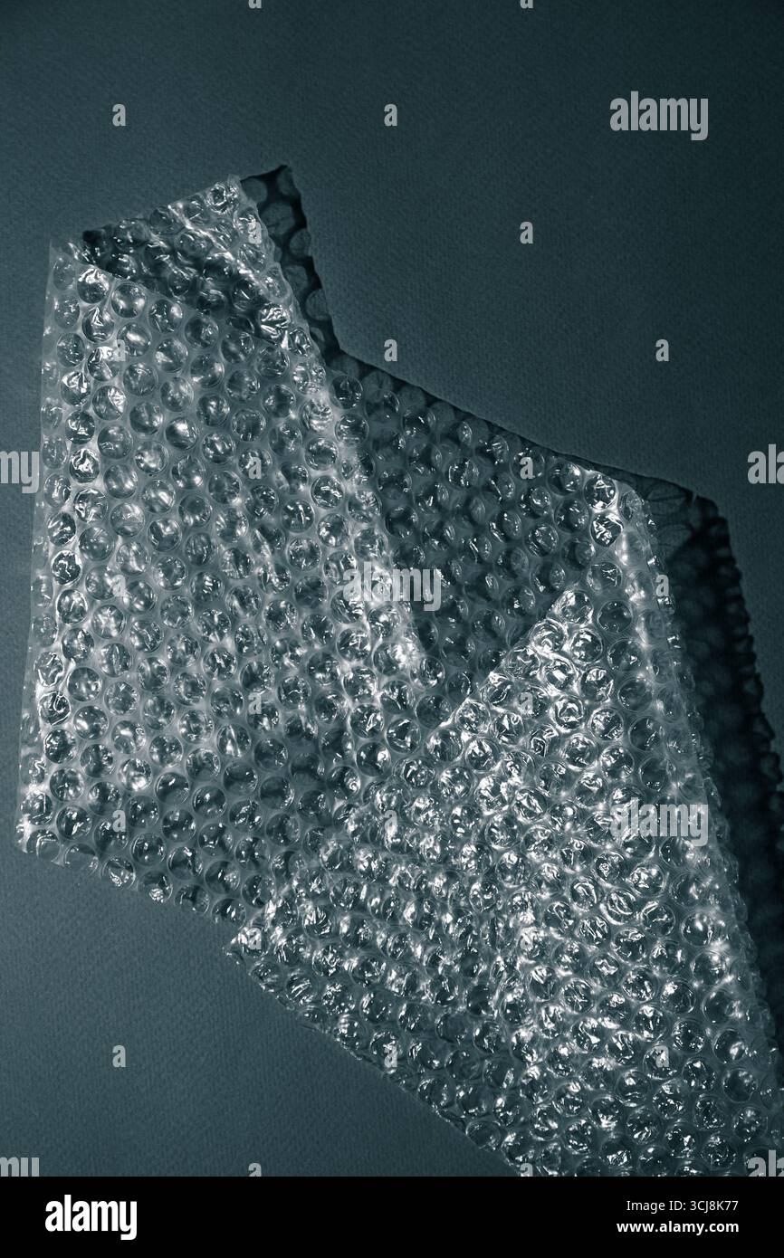 Nahaufnahme der Luftpolsterfolie, die geometrische Schatten auf einer Oberfläche erzeugt. Abstrakte Minimaltextur bei monochromem Licht. Stockfoto