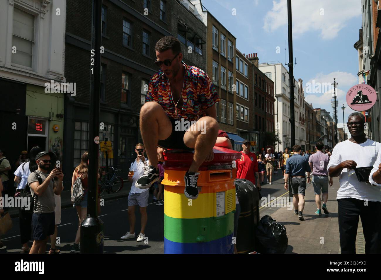 Ein Mann, der 2018 während Pride in London aus einem regenbogenbemalten Postkasten in der Old Compton Street in Soho sprang Stockfoto Ein Mann, der 2018 während Pride in London aus einem regenbogenbemalten Postkasten in der Old Compton Street in Soho sprang Stockfoto