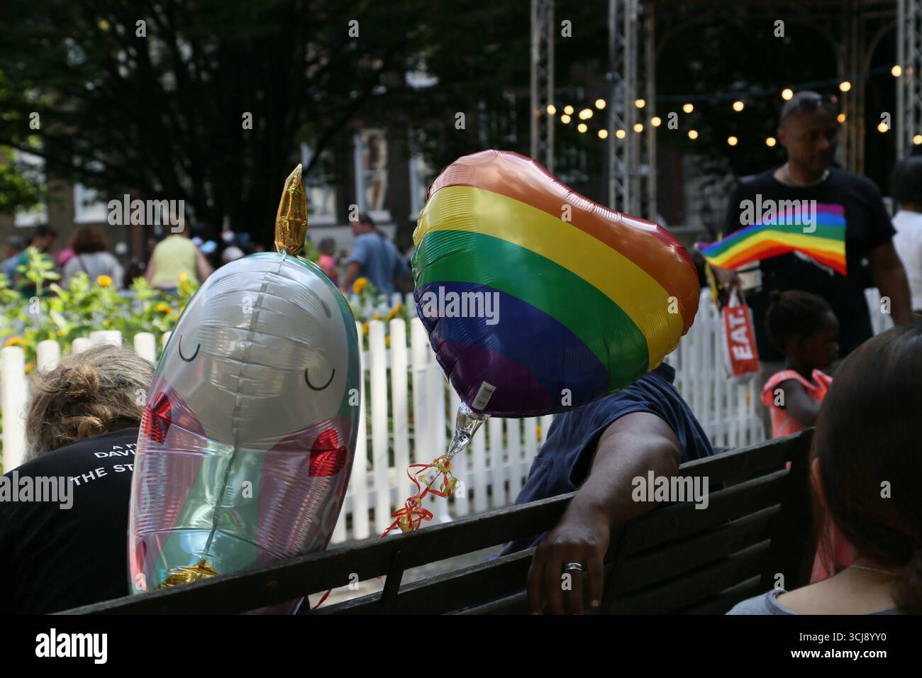 Ein Regenbogen- und Einhornballon bedeckt die Gesichter von Menschen, die 2018 auf einer Bank auf dem Golden Square in Pride in London saßen Stockfoto