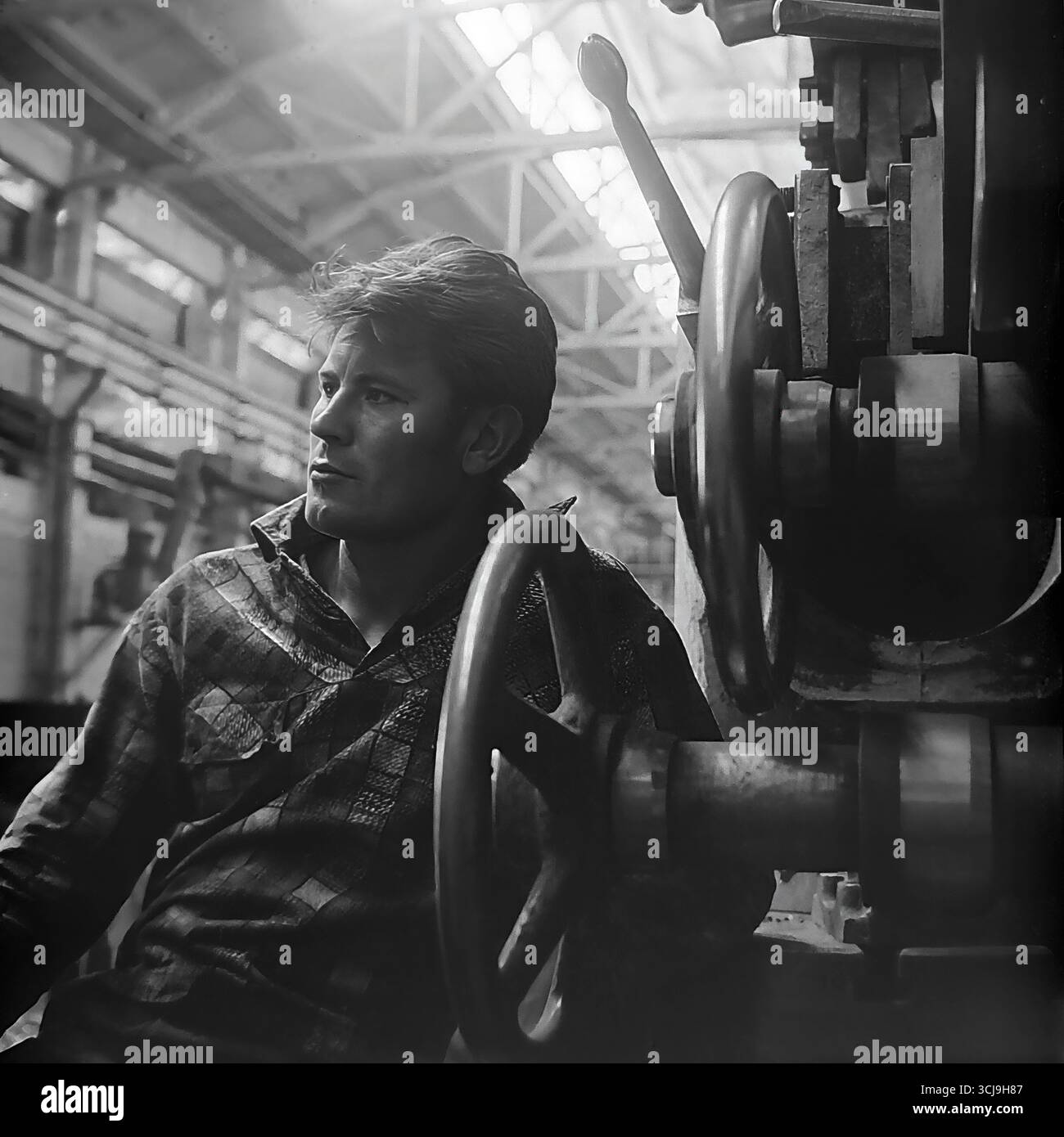 Künstlerisches Porträt eines jungen Arbeiters mit nachdenklichem Blick auf eine Werkzeugmaschine in einer Werkstatt eines Maschinenbauwerks in Sloviansk, 1970er Jahre Das Archivfoto im Stil des sozialistischen Realismus romantisiert das Bild des Werktätigen und schafft ein Porträt eines romantischen Helden. Dieses Foto ist ein Symbol für die kreative Macht und die friedlichen Hoffnungen des Donbas vor dem Krieg Stockfoto