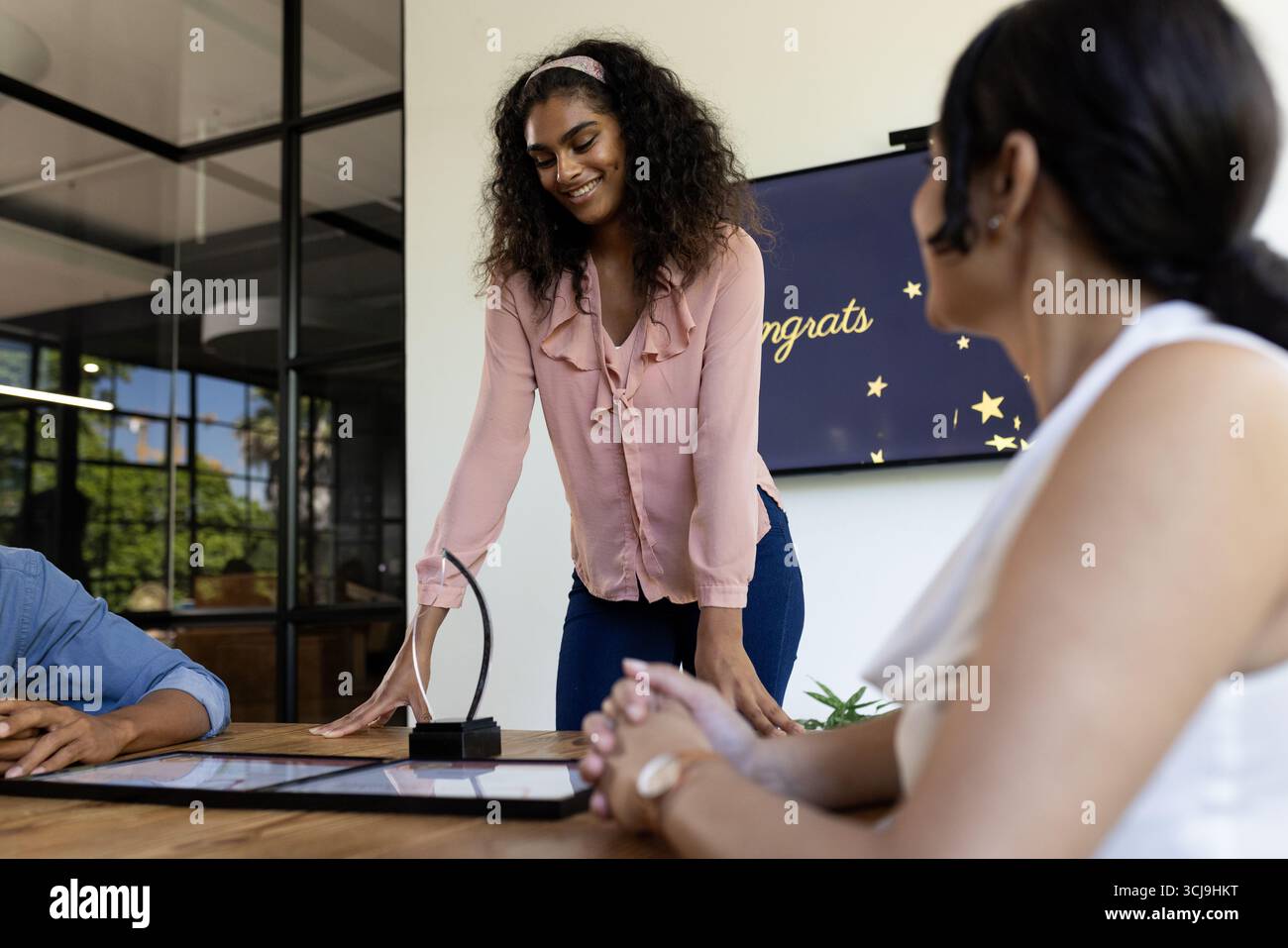 Lächelnde Frau prämiert bei einem modernen Bürotreffen mit Kollegen Stockfoto