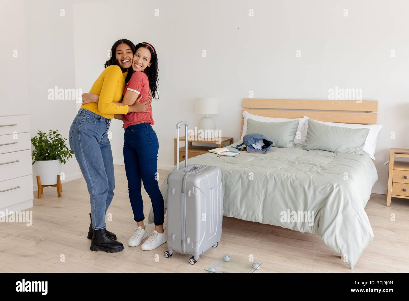 Freunde umarmen sich im Schlafzimmer mit Koffer und bereiten sich auf aufregende Reiseabenteuer vor Stockfoto